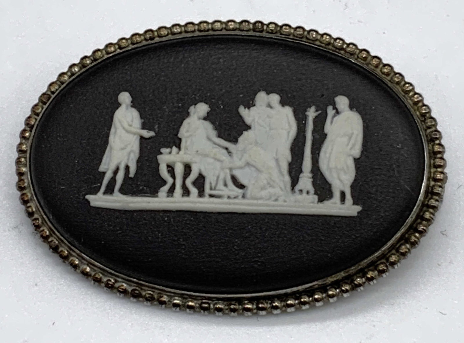 Vtg Wedgwood Black Basalt Grecian Brooch: Vintage Wedgwood black basalt brooch with white bas Relief Grecian figural motif. Setting tests for sterling silver using PuriTEST kit. Trademarked to underside. Made in England. Measures approx. 1 5/