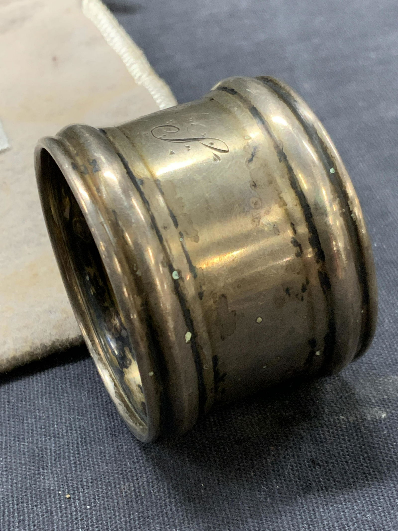 Sterling Engraved Napkin Ring W Dust Bag: Marked sterling on interior. Engraved on exterior O.P. Approximately 1 inch wide. Comes with tan toned Steuben dust bag. Total weight 0.57 ozt. Evident wearing and discoloration to napkin ring Sterlin