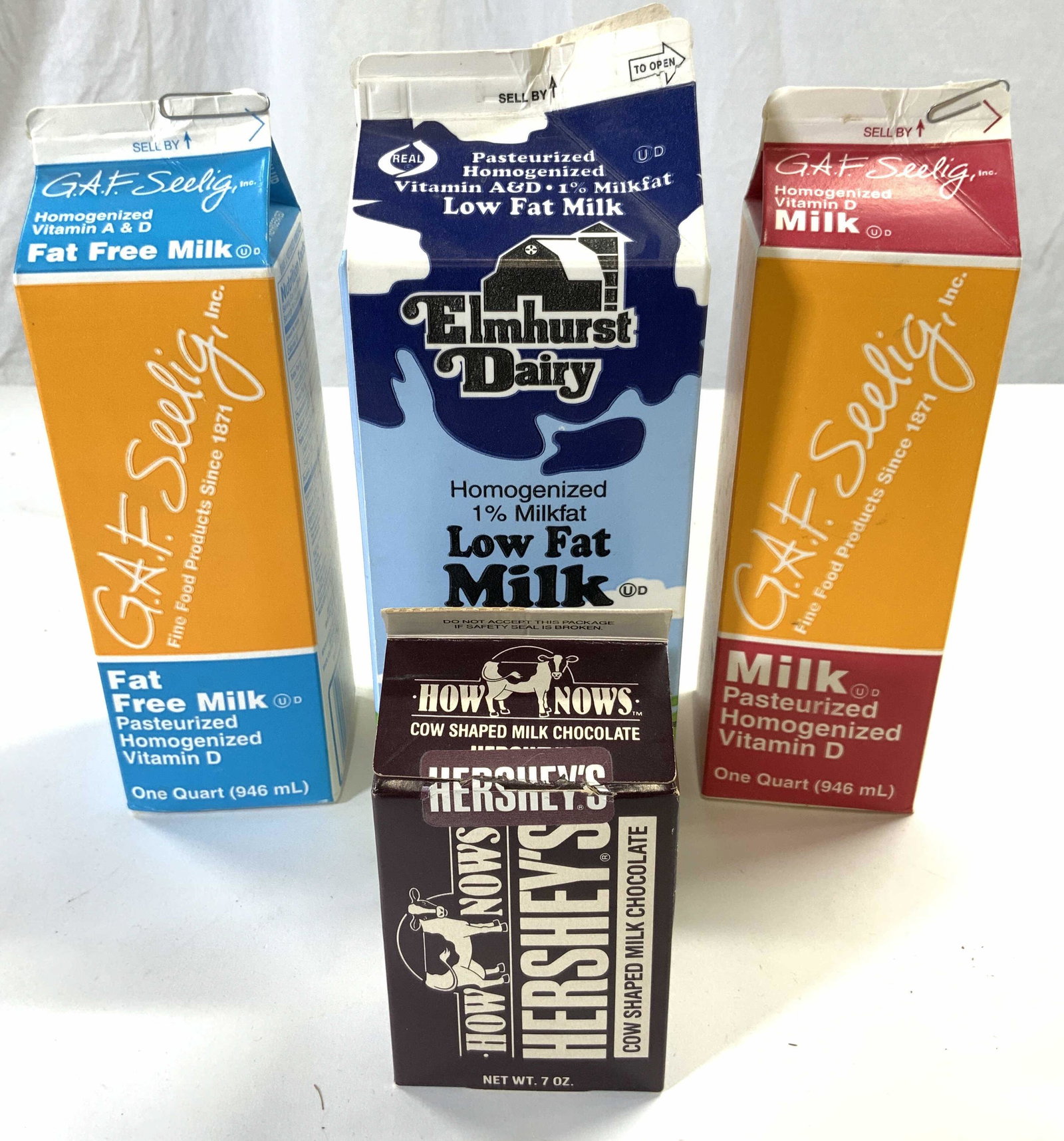 Vintage Collectible Milk Cartons: Lot includes 1 ELMHURST DAIRY Milk carton, 1 HOW NOWS HERSHEYS COW SHAPED MILK CHOCOLATE, & 2 GAF SEELIG INC MILK Cartons, 1 fat free. Largest measures approx 10 inches tall 3.75 inches wide & deep. M