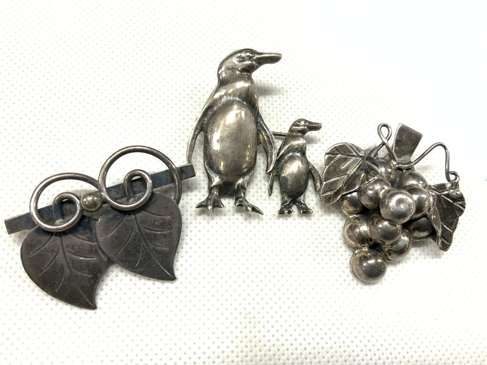 3 Art Deco & Animal Sterling Brooches: Lot of 3 sterling marked brooches. 1 art deco leaf brooch, marked George Jensen Inc. U.S.A Sterling. 1 brooch that resembles a bunch of grapes on the vine, marked 925 on backside, and another brooch w