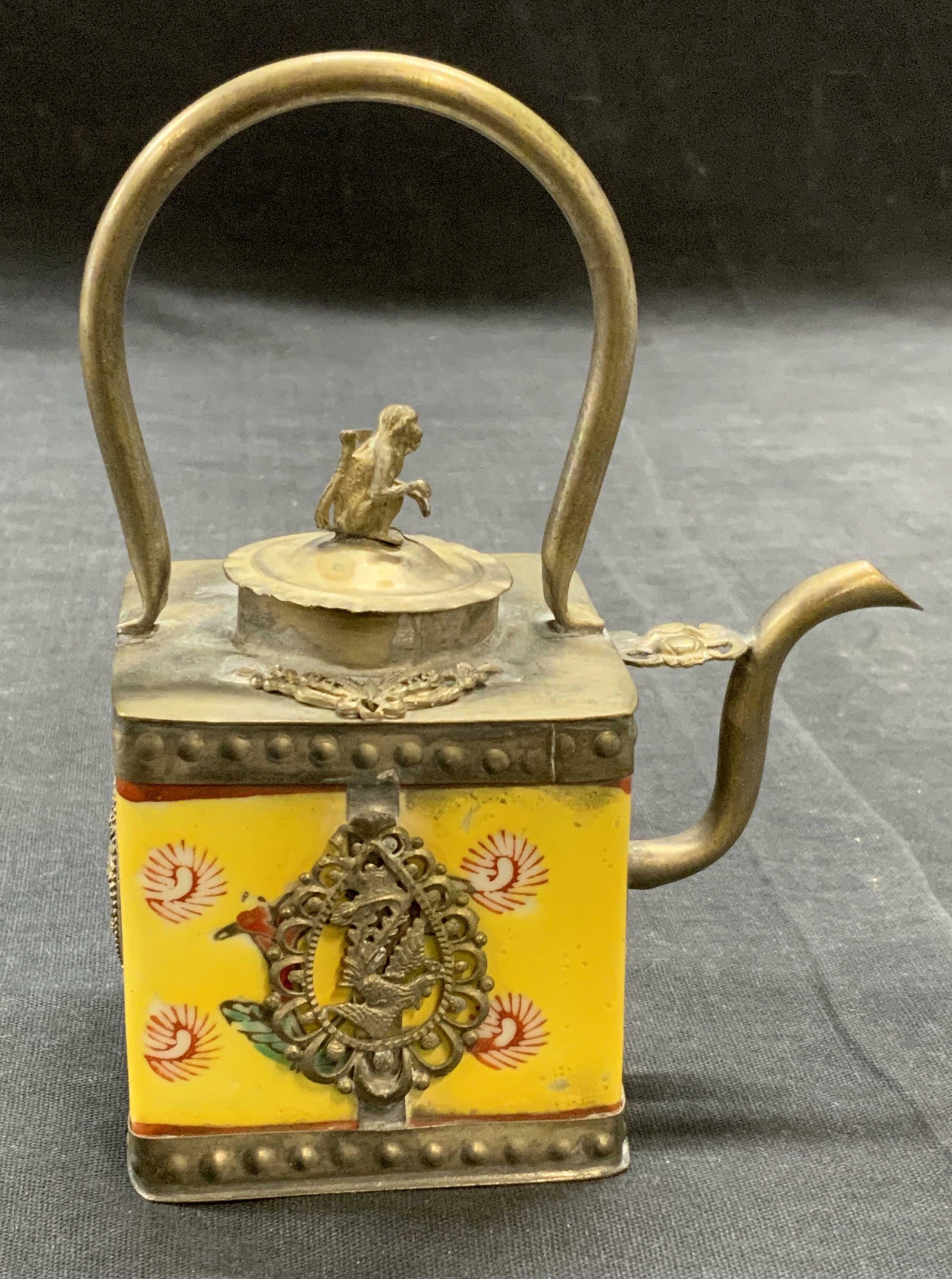 Stamped Chinese Porcelain & Metal Teapot: Stamped Chinese porcelain and metal teapot in yellow with monkey, Phoenix, and dragon motif. Stamped to underside. Some surface wear consistent with exposure. Measures approx. 3.75 x 2.25 x 5 inches. 