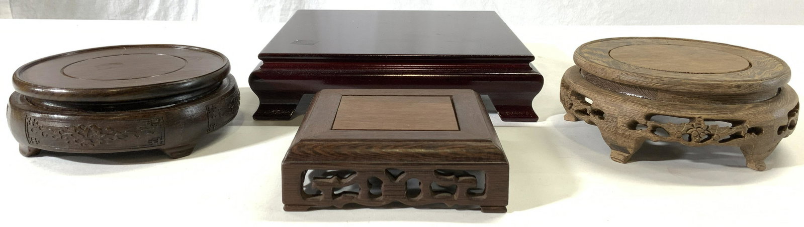 Lot 4 Carved Wooden Asian Stands Pedestals: Lot includes 4 pedestals. Each are wooden. Includes 1 is mahogany toned with feet, 1 square shaped with pierced detail, 1 circular shaped with feet & pierced detail, & 1 with feet & scroll relief deta