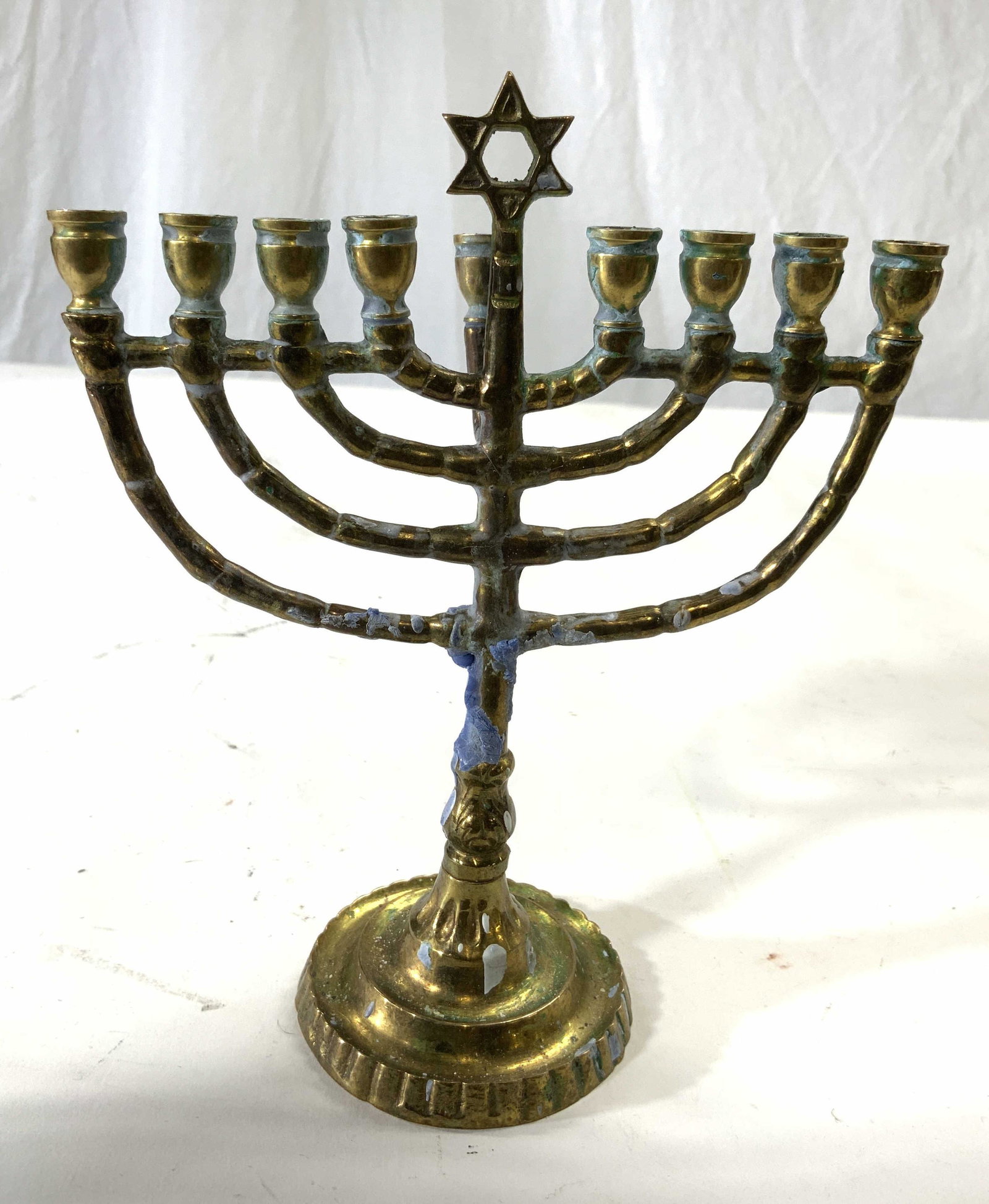Vntg Brass Judaica Menorah W Star Of David: Menorah is vintage possibly antique. Piece is gold toned and brass. Top center had Star of David. Base is circular shaped. Piece measures approximately 7 inches tall 6 inches wide 2.75 inches deep. Me