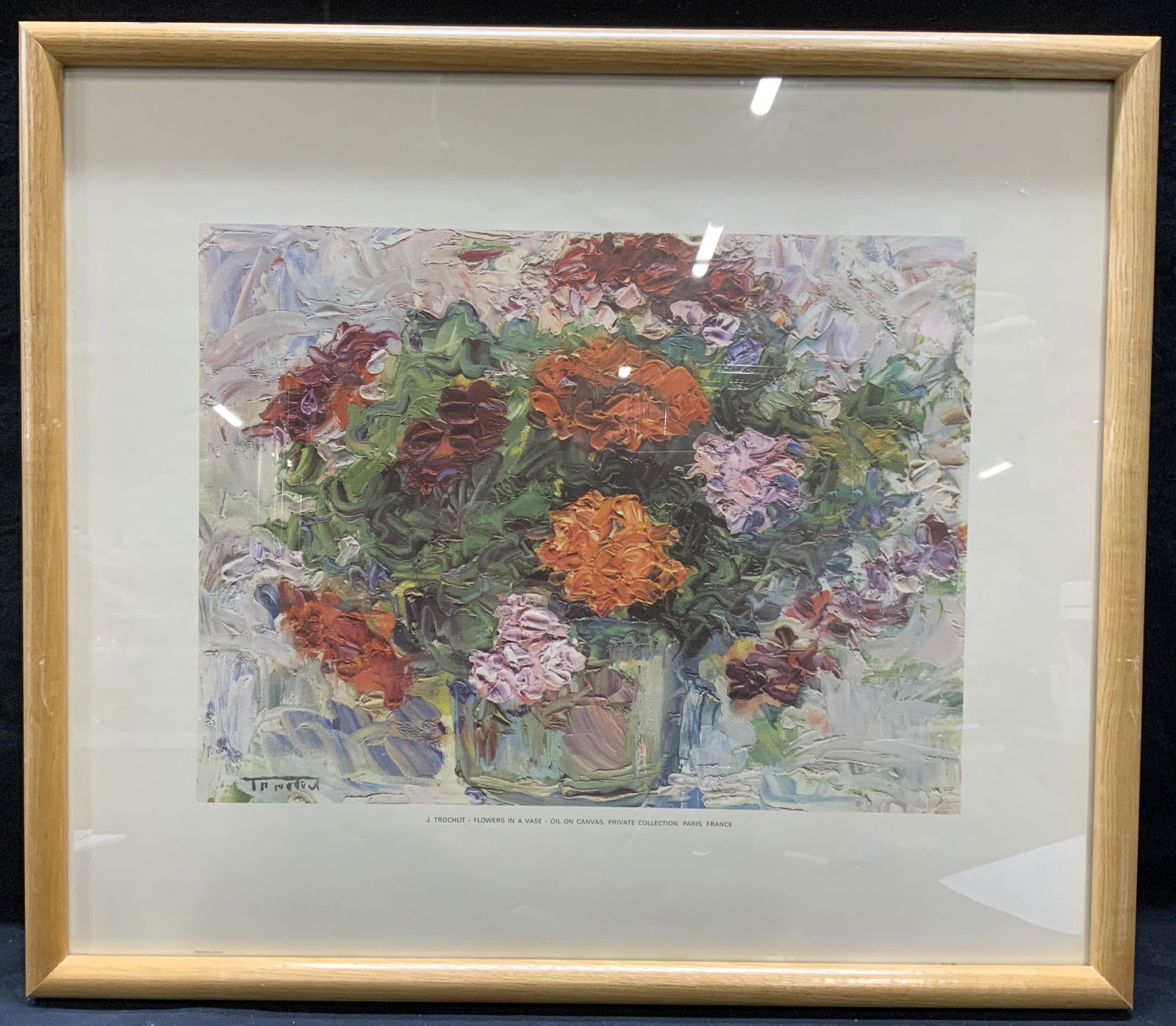 J Trochut Still Life Flowers Fine Art Lithograph: J. Trochut framed fine art lithograph. Labeled at lower center. Subject depicts still life with floeers in a vase in hues of red, pink, orange, and green. Professionally framed in light wood frame. No