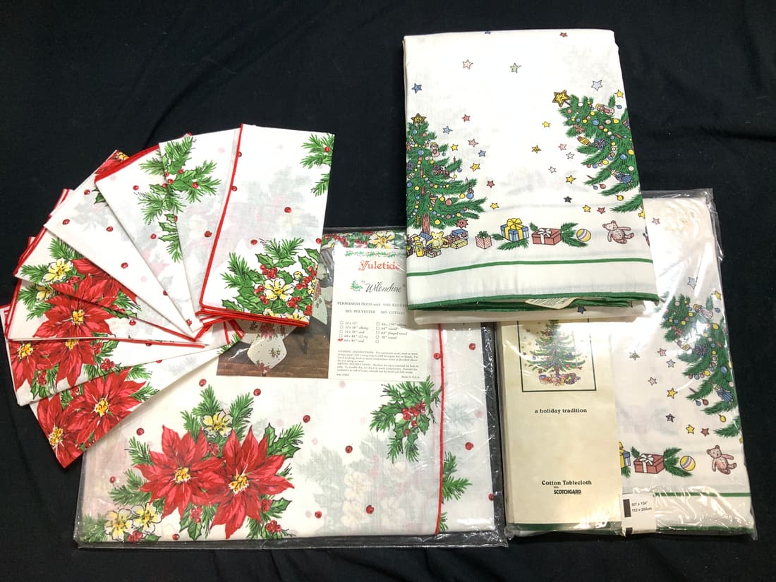 Lot 22 Christmas Cotton Tablecloths,Napkins, NIP: Yuletide by Wilendure oval tablecloth and napkin set , white with poinsettias, holly and Berry, and pine branches. Table cloth Measures 60 x 84 inches. 50% polyester, 50% cotton . Permanent press with