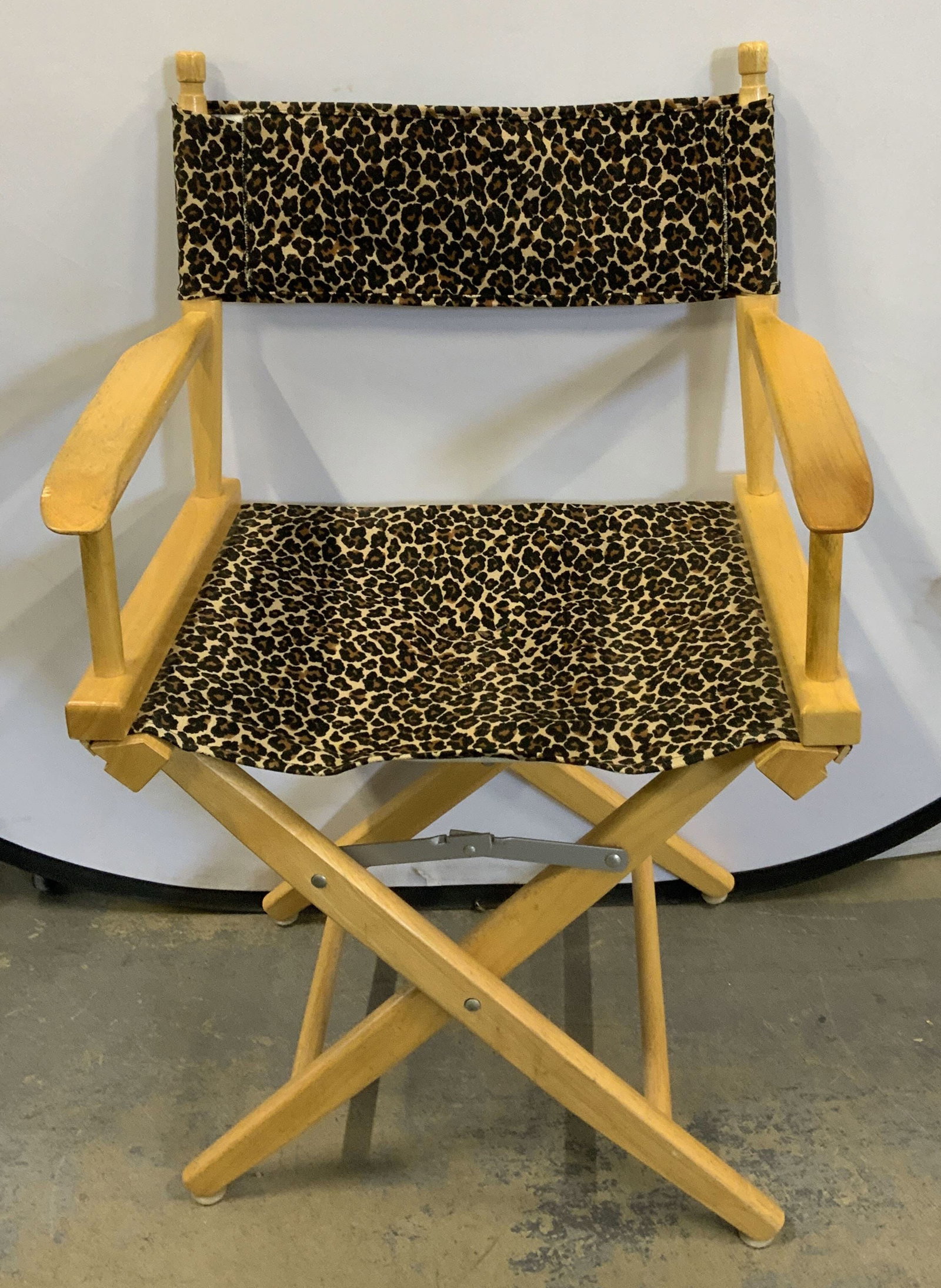 Wood Cheetah Directors Chair: Wood framed directors chair with cheetah print fabric seat and back rest. Some surface wear consistent with exposure. Measures approx, 22.5 x 15.75 x 35.5 inches. Chair, directors chair, folding chair