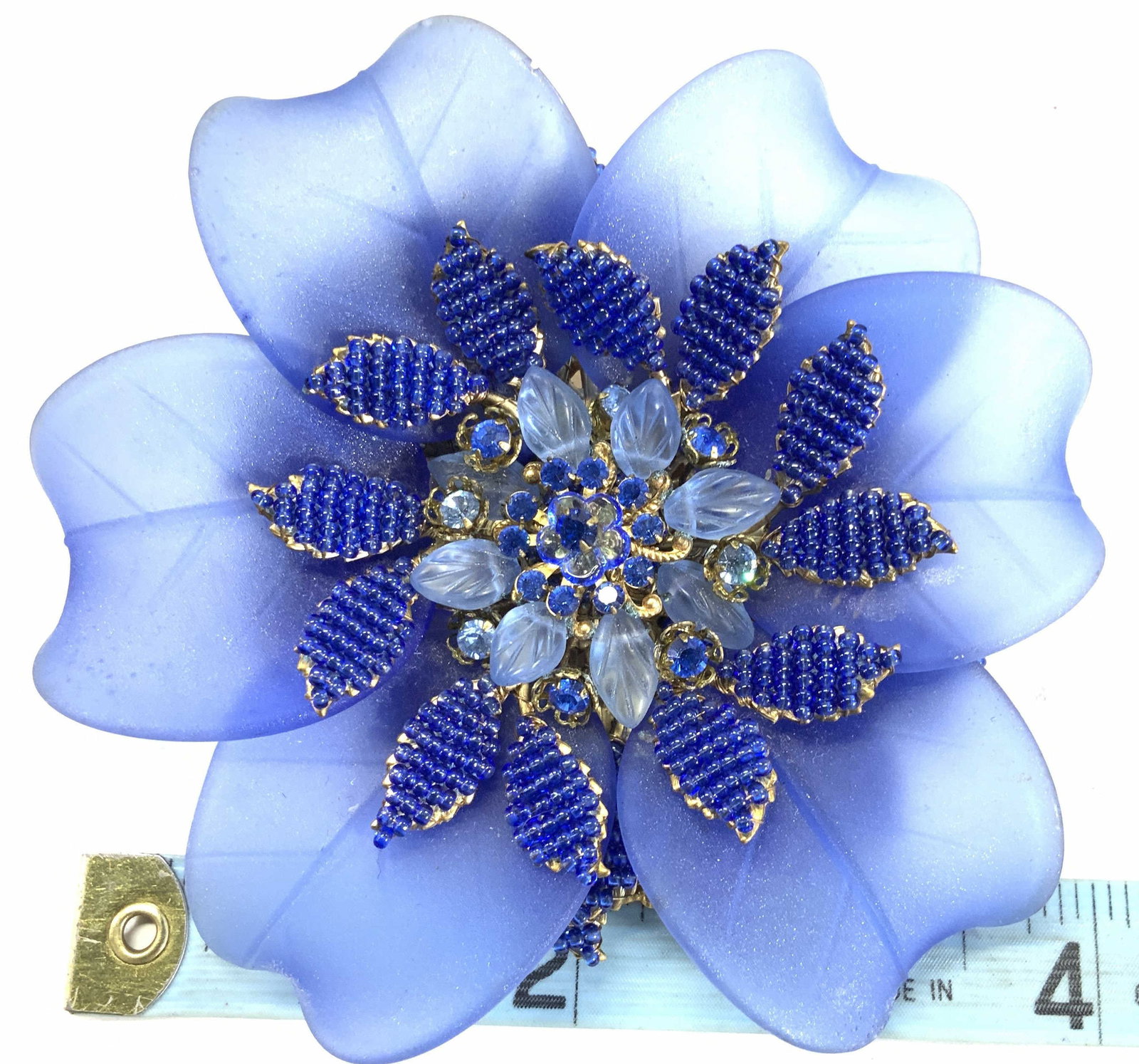 STANLEY HAGLER Signed Glass Flower Brooch: STANLEY HAGLER signed cobalt blue glass flower brooch with AB crystals and seed beads, all blue set in contrasting gold tone metal. One petal had been re glued. 4.5 in. diameter. Heavy piece. Comes in