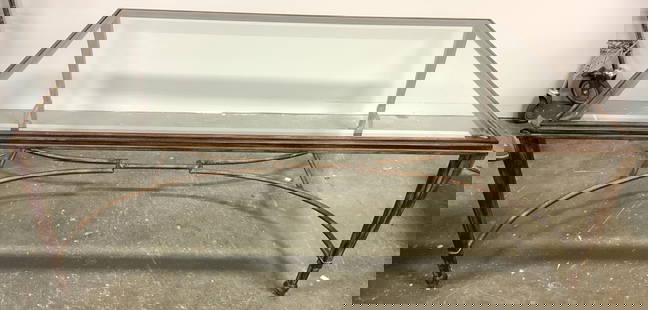 Iron Base Glass Top Coffee Table: Coffee table has iron base/frame. Piece has beveled glass top. Legs have double arch stretcher in between legs. Legs taper inward towards bottom. Measures approx 54 inches long 36 inches deep 19 inche