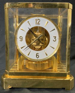 JAEGER COULTRE ATMOS Brass Mantel Clock: Clock face reads JAEGER COULTRE ATMOS SWISS MADE. Clock is gold toned with white clock face. Center has rotating pendulum. Clock is brass and glass. Front window has small lever to remove glass. Piece