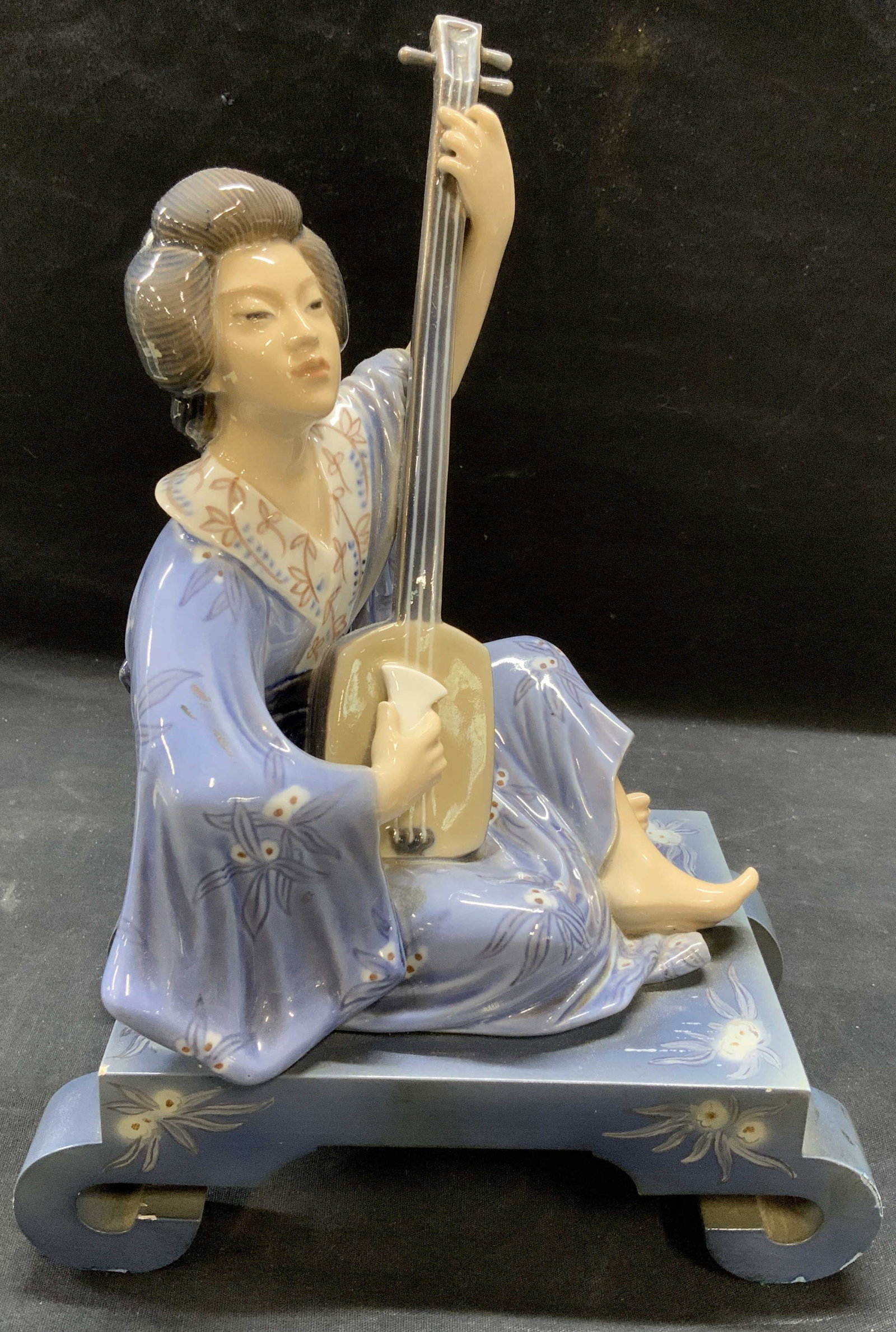 Dahl Jensen Porcelain Geisha Figurine: Dahl Jensen porcelain geisha figurine mounted on wood base. Trademark not visible. Some general surface wear, pitting and imperfections to glaze on figure. Evident losses to paint on wooden base. Meas