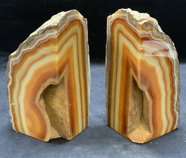 Pair Cut Natural Geode Bookends: Pair of cut orange toned natural geode bookends. Larger piece measures approx. 4 x 2.5 x 6.75 inches. Some surface wear to each consistent with exposure. Pieces have weight. Geode, natural geode, cut