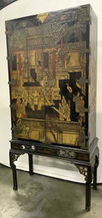 Vintage Lacquered Wooden Asian Cabinet: Cabinet is vintage and lacquered wood. Piece is black with intricate multi toned architectural, crane, & figural detail. Cabinet has gold toned hardware, appears to be brass. Cabinet sits on top of ba