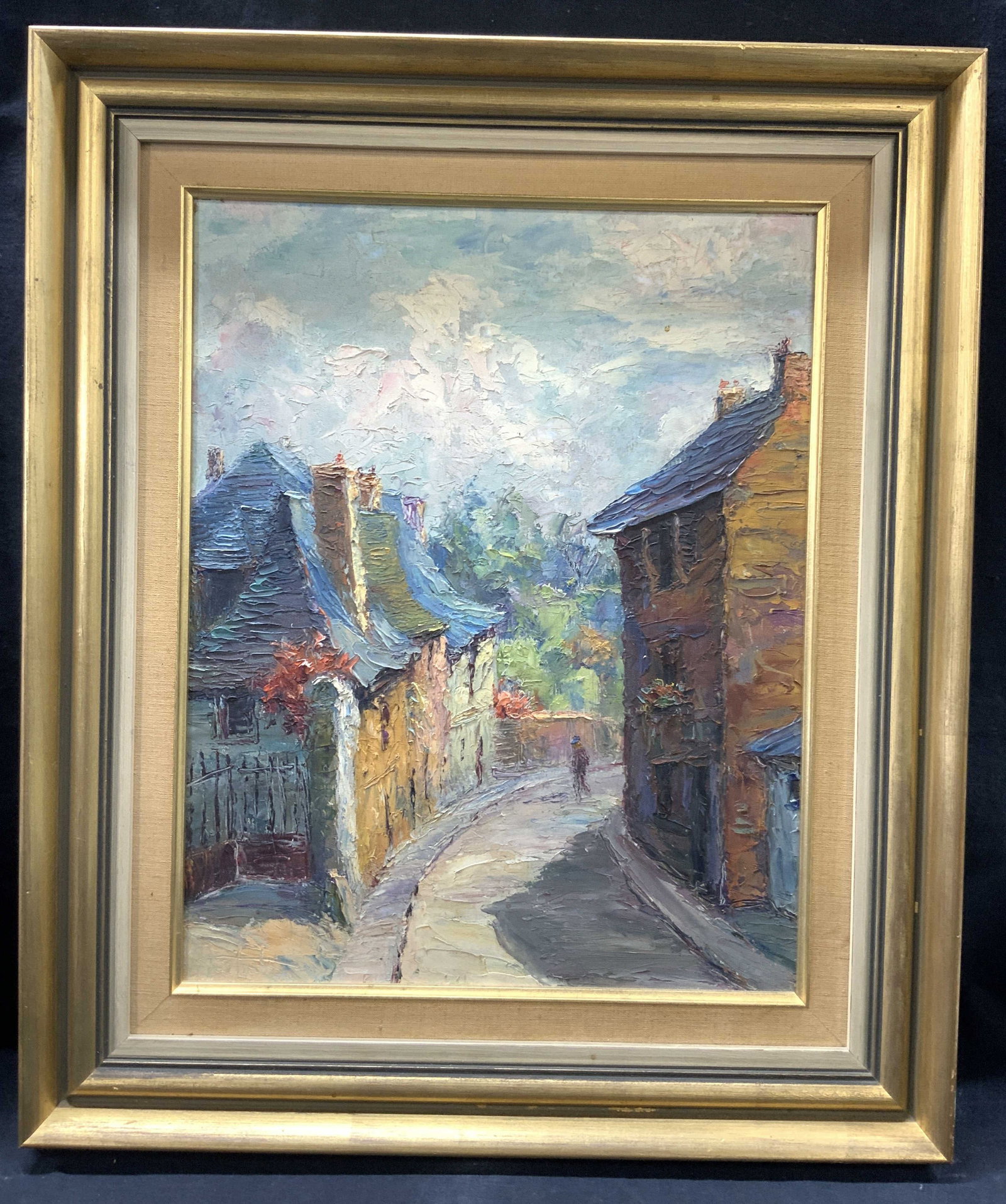 Signed Street Scene Oil Painting: Signed in lower left corner, illegibly Subject depicts a street scene on a curved road in vibrant colors Framed in gold metal leafed wooden frame with linen inner edges Approximately 21 x 18 inches wi