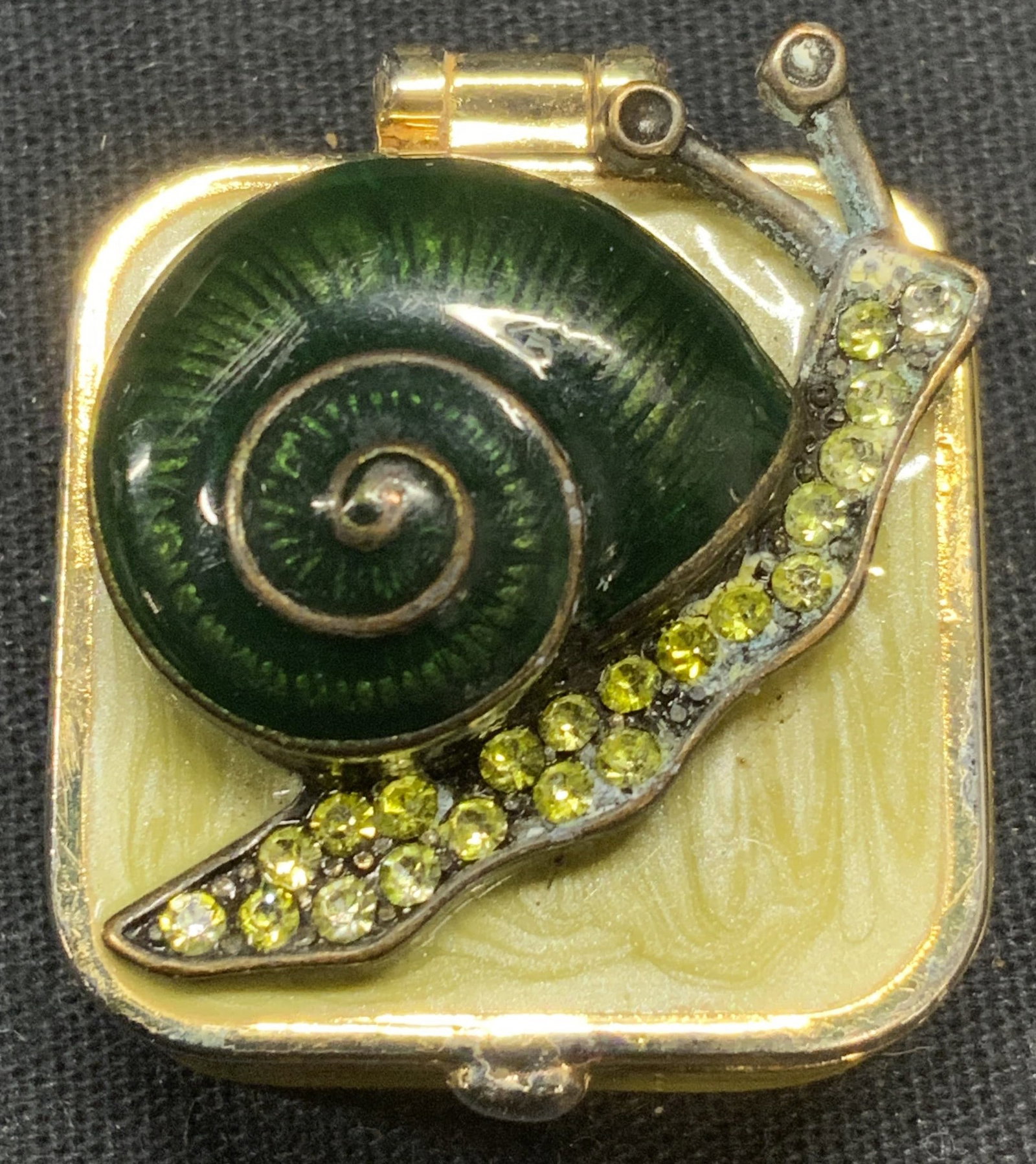 Niquea D Snail Enamel Crystal Pill Box: Niquea D. enameled Metal and crystal decorated snail pill box. Trademarked to underside. Some surface wear consistent with exposure. Measures approx. 1 x 1 x 5/8 inches. Niquea d, Niquea d pill box, e