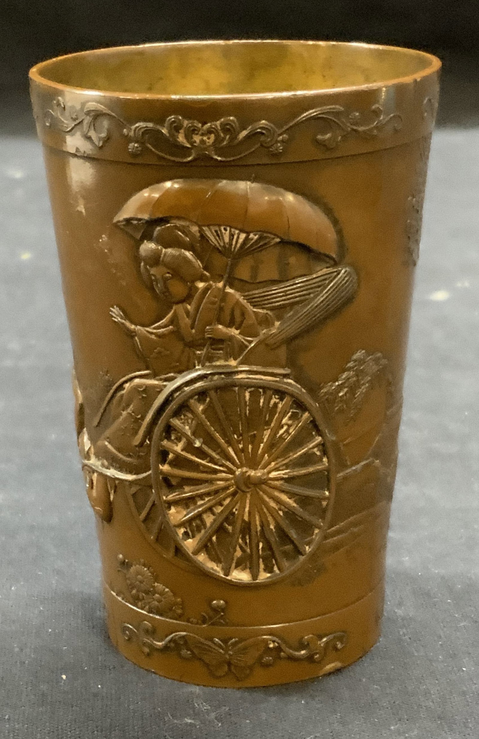 Embossed Asian Figural Mixed Metal Cup: Embossed Asian figural mixed metal cup. Brass and white metal. Surface wear consistent with exposure. Measures approx. 2.25 x 3.5 inches. Asian decorative arts, decorative arts, home decor, home acces