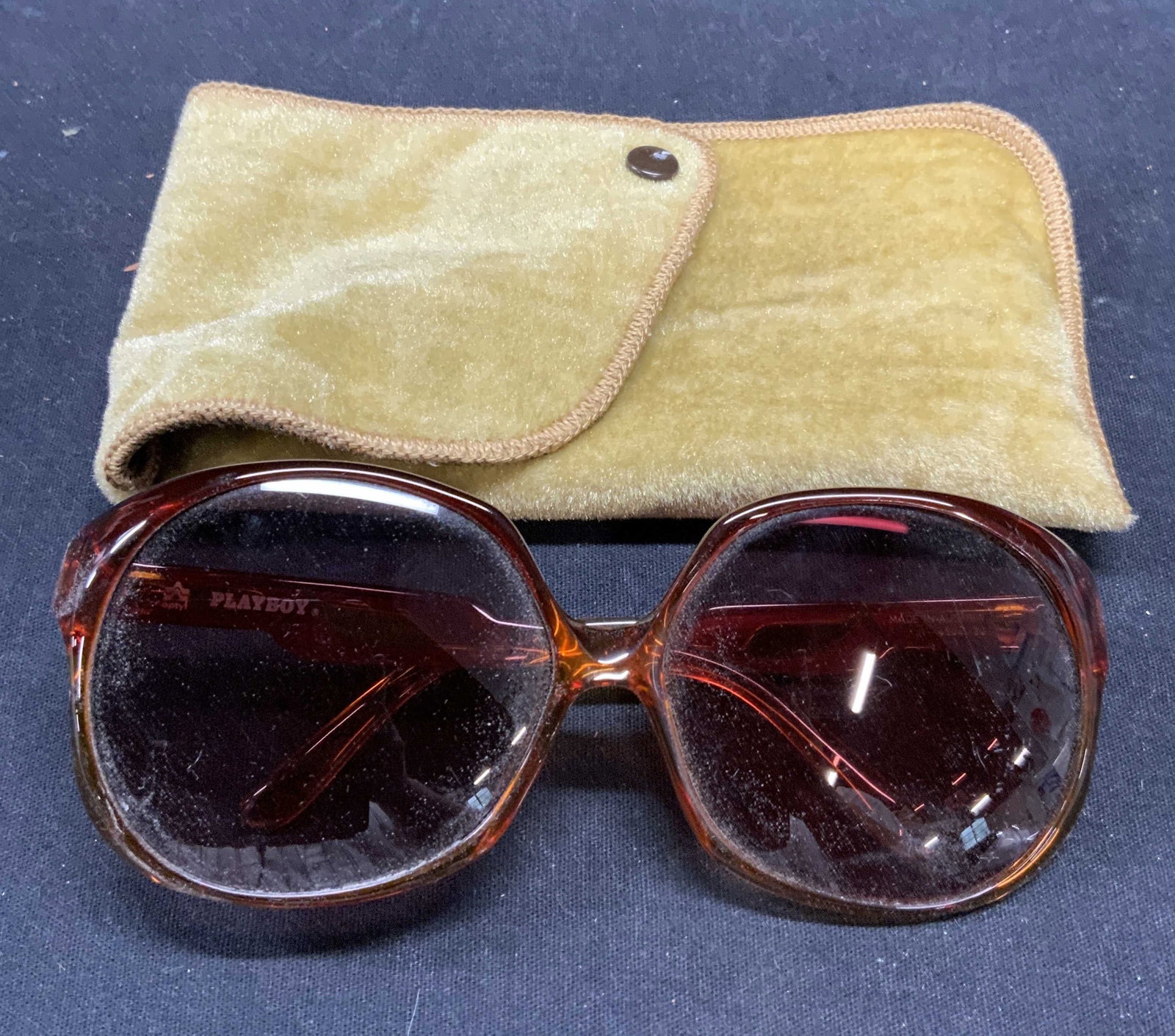Vintage Playboy Amber Frame Sunglasses: Vintage Playboy amber acrylic frame sunglasses and pouch. Designer label to arm. Surface wear consistent with exposure. Measures approx. 5 x 5.5 x 2.25 inches. Playboy, playboy sunglasses, ladies desi