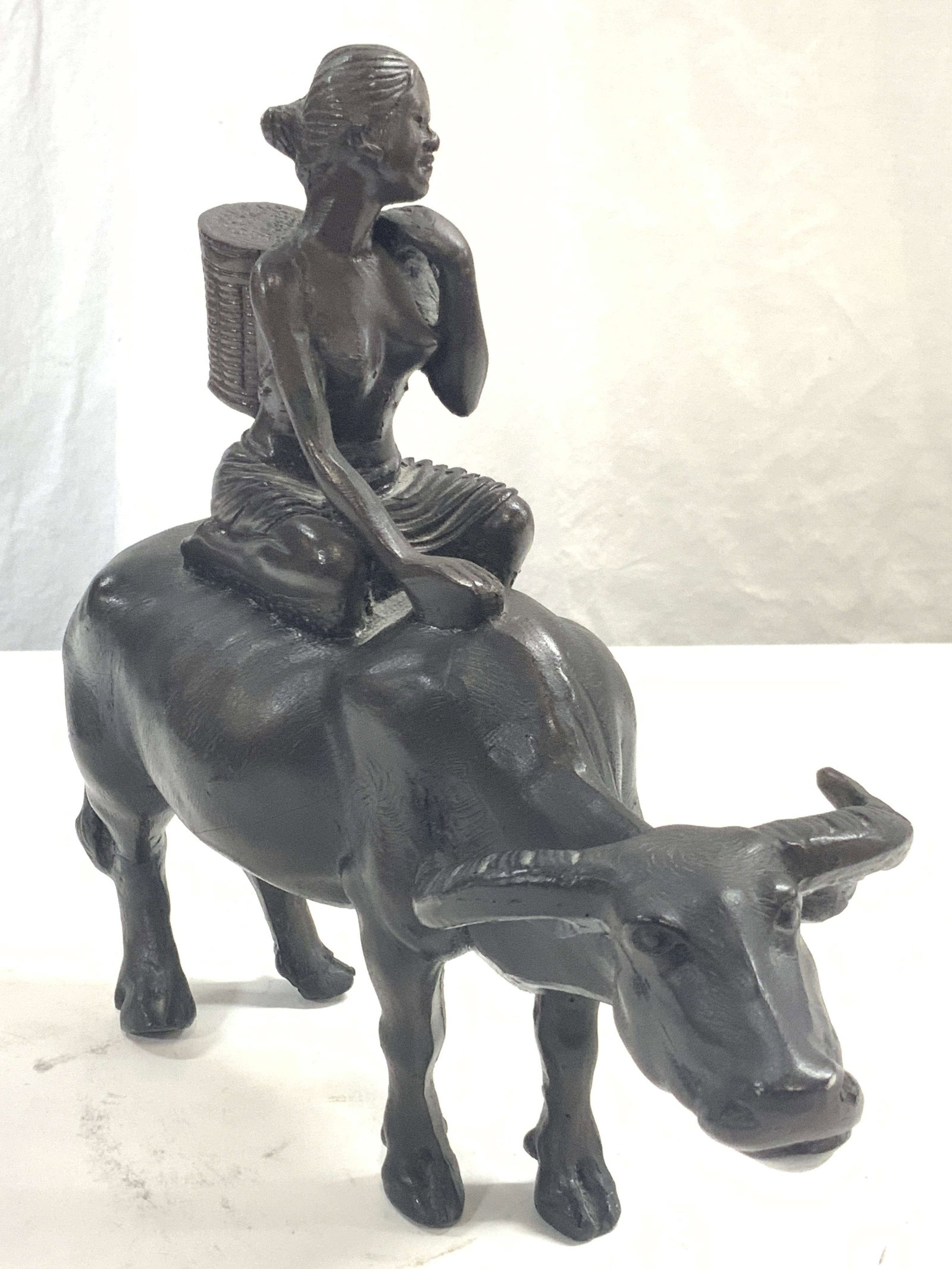 Plaster Lady On Water Buffalo Figural: Black painted plaster made figure of a woman with a basket on her back sitting atop a water Buffalo. Approximately 9.25 inches tall and 11 inches long. Minor wearing to Buffalo. Plaster figure, figuri