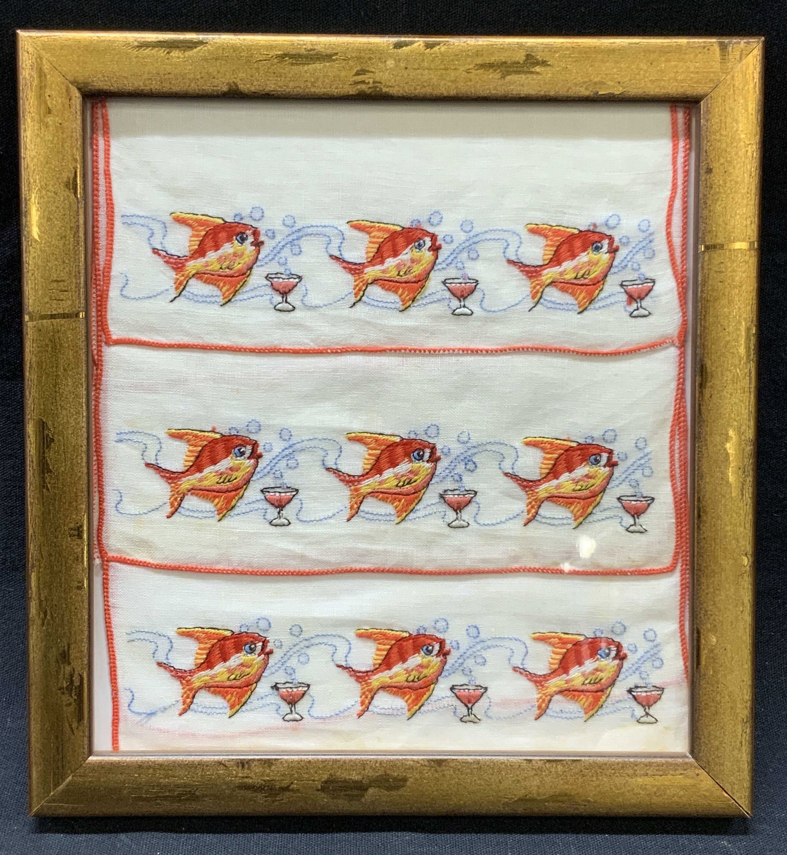 Framed Gold Fish Embroidery Panel: Framed embroidery panel depicting a gold fish with a martini glass in front of them Framed in gold metal leafed wooden frame approximately 6.75 x 6.25 inches, window measures 5.5 x 5.25 inches. Modera