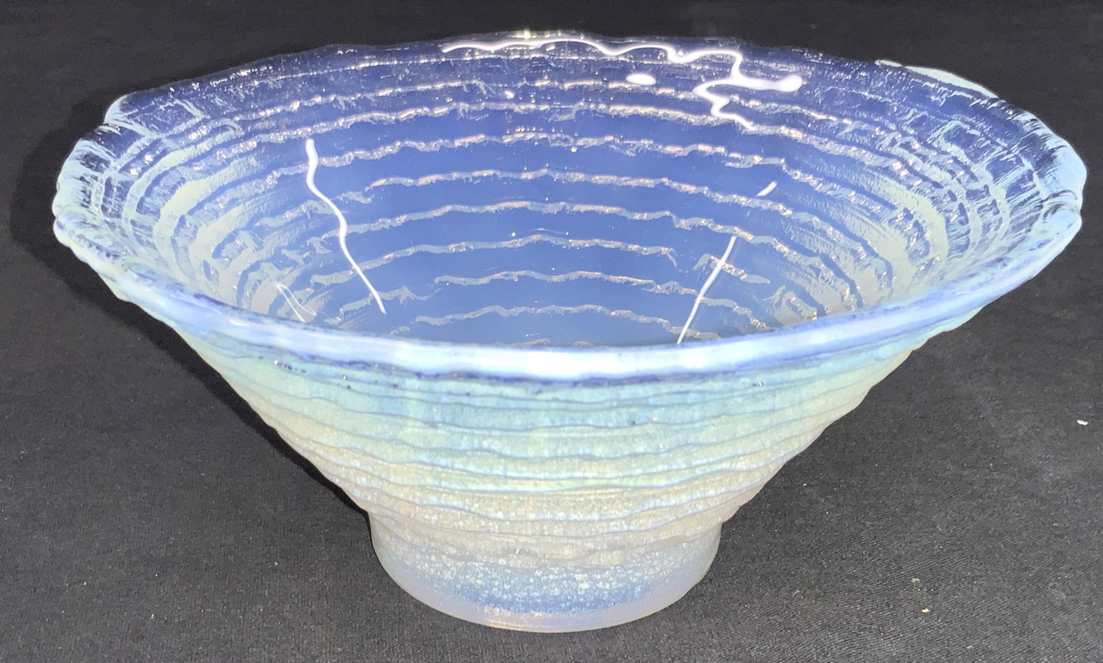 Opalescent Glass Textured Bowl: Art glass bowl with blue white gradient and textured layers to exterior and wavy rims. Approximately 3 inches tall and 6.5 inch diameter. Minor surface wearing. Art glass bowl, art glass decor, nut bo