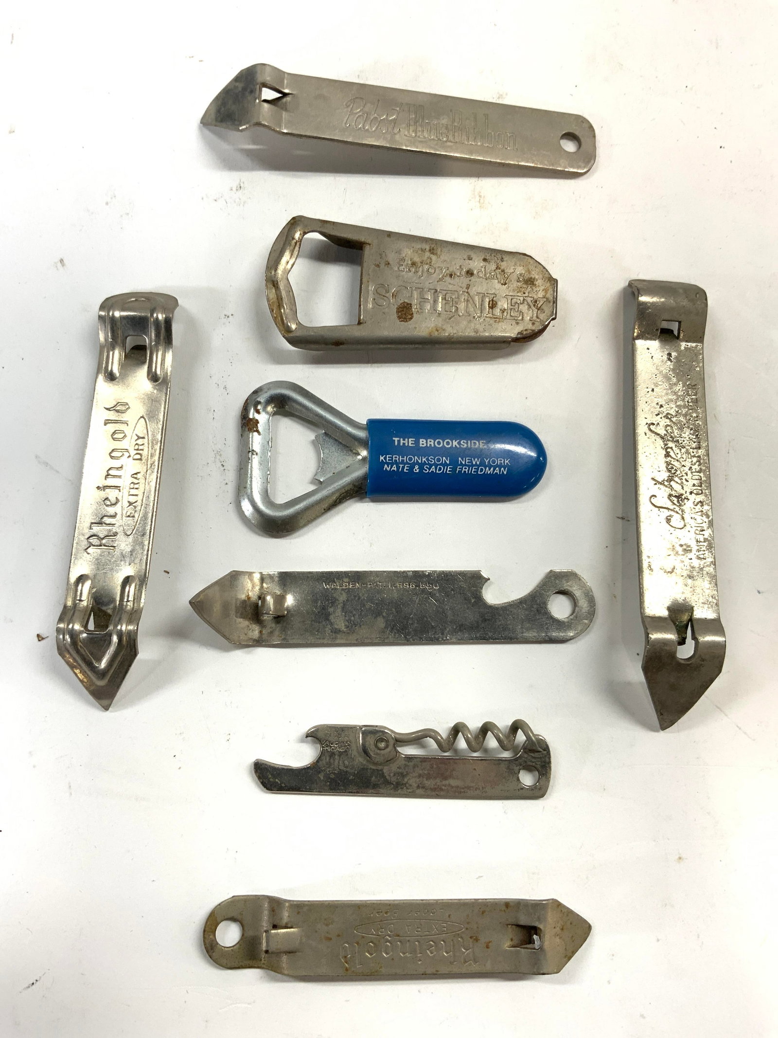 Lot 8 Vintage Metal Promotional Can Openers: Lot includes 5 can openers, 2 bottle openers, & 1 wine cork.includes brands such as PABST BLUE RIBBON, HARVARD ALE, SCHENLEY, SCHAFER, RHEINGOLD, & THE BROOKSIDE. Largest opener measures approx 4.75 i