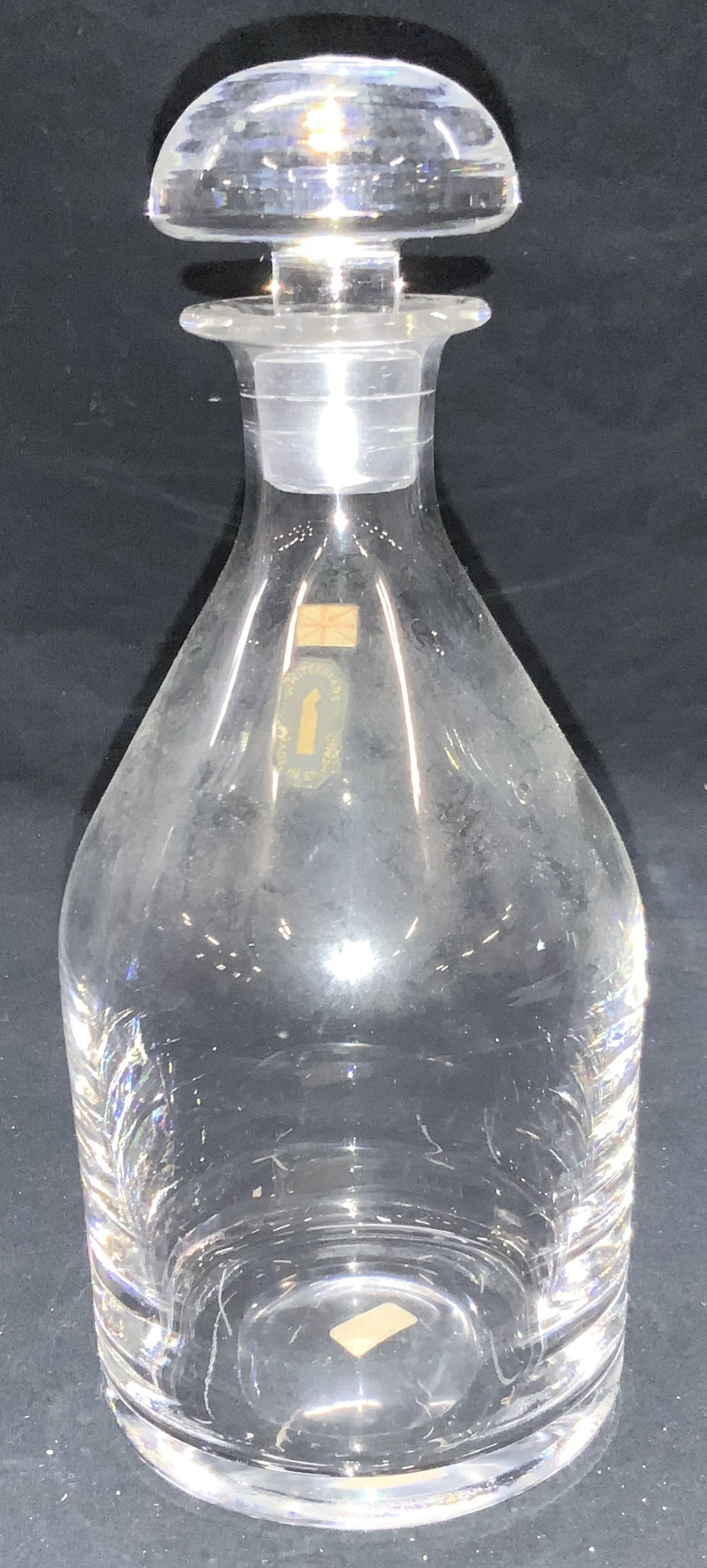 Vintage Whitefriars Clear Glass Decanter, England: Marked on sticker that reads Whitefriars, made in England. Clear glass decanter with dome shaped stopper. Approximately 9.5 inches tall. Moderate surface wear. Vintage clear glass decanter, glass deca