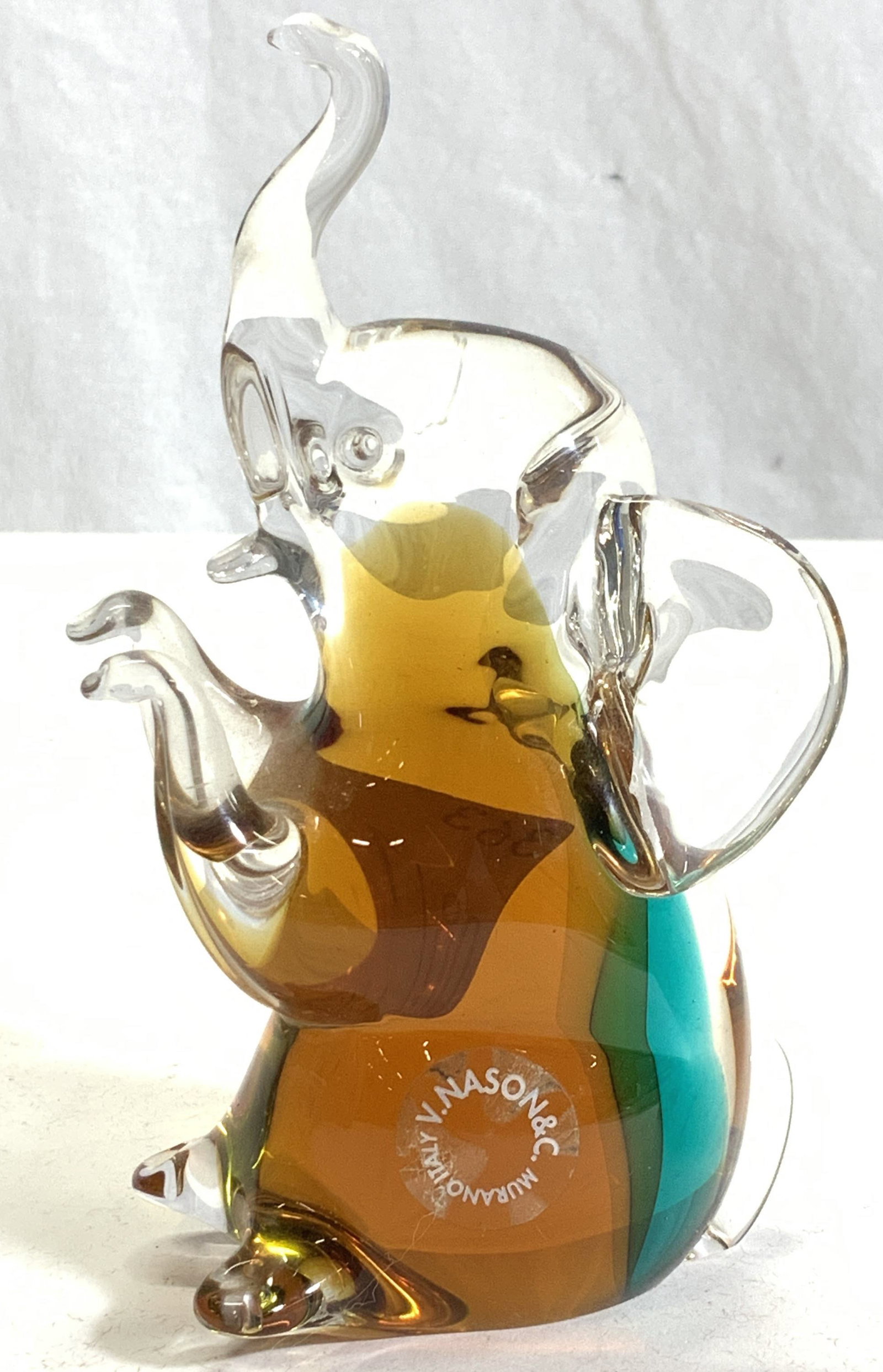 V. NASON&Co MURANO Art Glass Elephant, Italy: Vintage Murano Glass Elephant Figural/ paperweight. Original label sticker is affixed to glass. Reads V. NASON&Co MURANO ITALY. Measures 5.75 in. Ht x 3 in. D x 2.25 in. Wide. Vintage Murano glass Ele