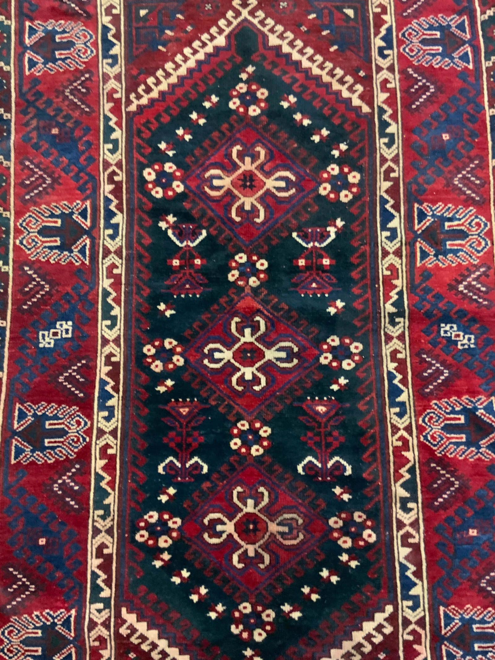 DOSEMEALTI Vintage Turkish Wool Rug, Istanbul: A vintage Turkish rug crafted from wool. Primarily deep red, blue, and off white hues. Geometric and floral designs throughout. Tag to reverse reads MADE IN TURKEY, ORIGIN DOSEMEALTI, MATERIAL WOOL, I