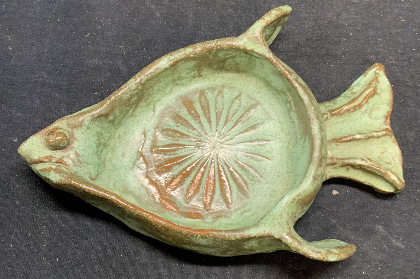 Green Art Pottery Fish Plate: Green toned art pottery fish plate/wine bottle coaster. Measures approx. 9 x 6 x 1.5 inches. Some surface wear consistent with exposure. Art pottery, art pottery fish plate, fish plate, fish wine coas