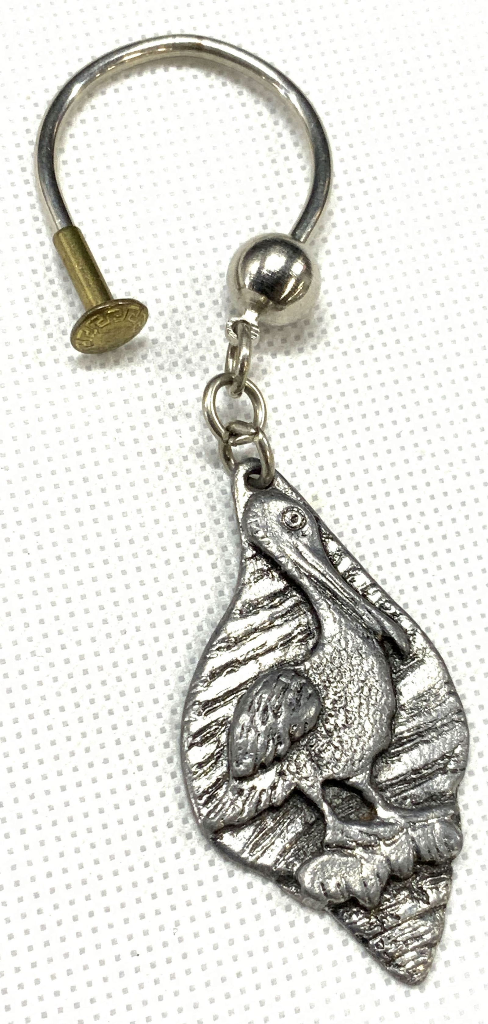 Metzke Stamped 1976 Pewter Pelican Keychain: Marked in backside Metzke 1976 Depicts a raised image of Pelican within pewter with white metal loop. Approximately 4 inches long. Minor wearing due to age and use. Pewter keychain, Metzke keychain, P