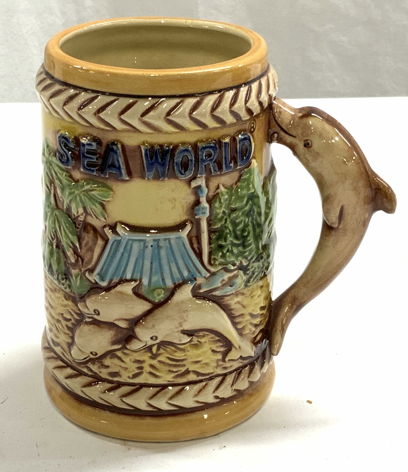 Vintage Japanese Ceramic Sea World Mug: Vintage Japanese ceramic Sea World mug. Dolphin, whale, and ship captain motif. Marked Japan to underside. Some surface wear consistent with exposure. Measures approx. 3.25 x 5.25 inches. Sea world, s