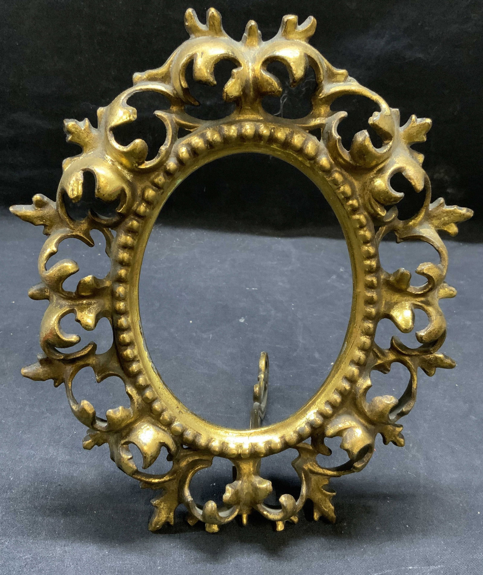 Vintage Brass Oval Scroll Frame: Vintage brass oval shaped frame with scroll border. Surface wear consistent with exposure. Measures approx. 9 x 7.5 inches. Piece has weight. Frame, brass frame, scroll frame, oval frame, table frame,