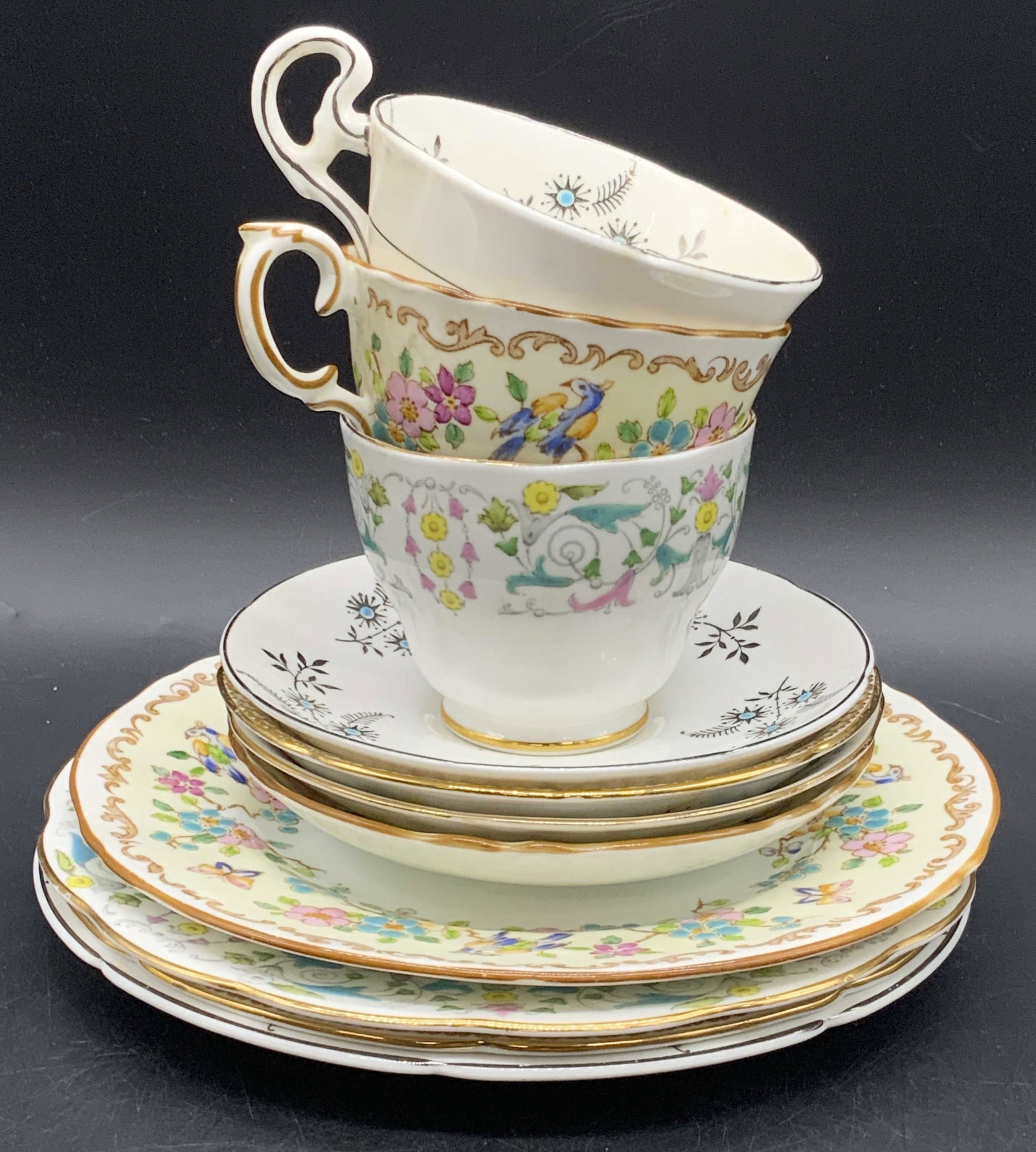 11 Vintage Bone China Teacups, Saucers, & Plates: Group lot of bone china. Three teacups, four saucers, and four plates. Pieces feature some hand painted elements, florals, foliage, and avian motifs. Brands include RAVENNA ROSLYN FINE BONE CHINA ENGL