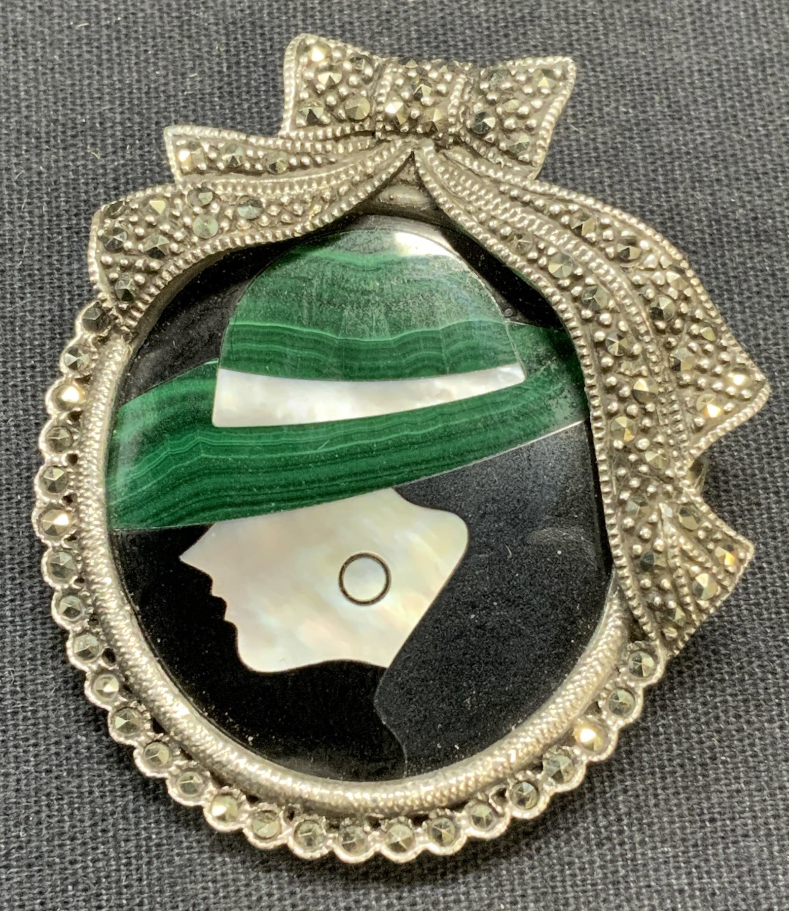 Sterling Silver Pietra Dura Cameo Brooch: Sterling silver Pietra Dura cameo brooch with mother of pearl, malachite, and marcasite decoration. Hinge pin to underside. Marked 925 to underside. Some surface wear consistent with exposure. Measure