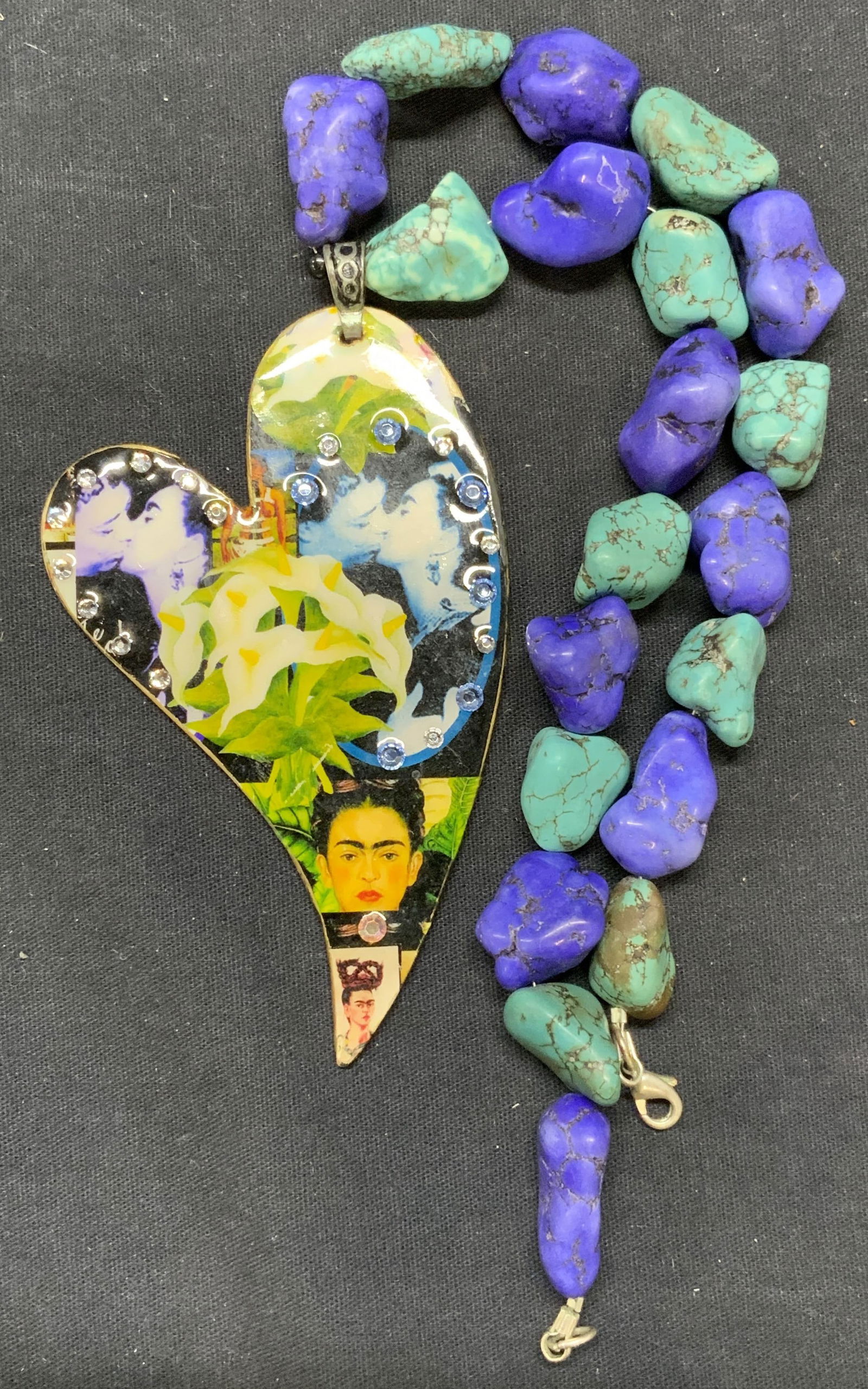 Signed Turquoise Beaded Frida Kahlo Necklace: Signed pendant necklace. Turquoise beaded necklace with wood heart pendant. Frida Kahlo collage and crystal decoration to pendant. Signed to reverse of pendant, illegible. Measures approx. 17.5 inches