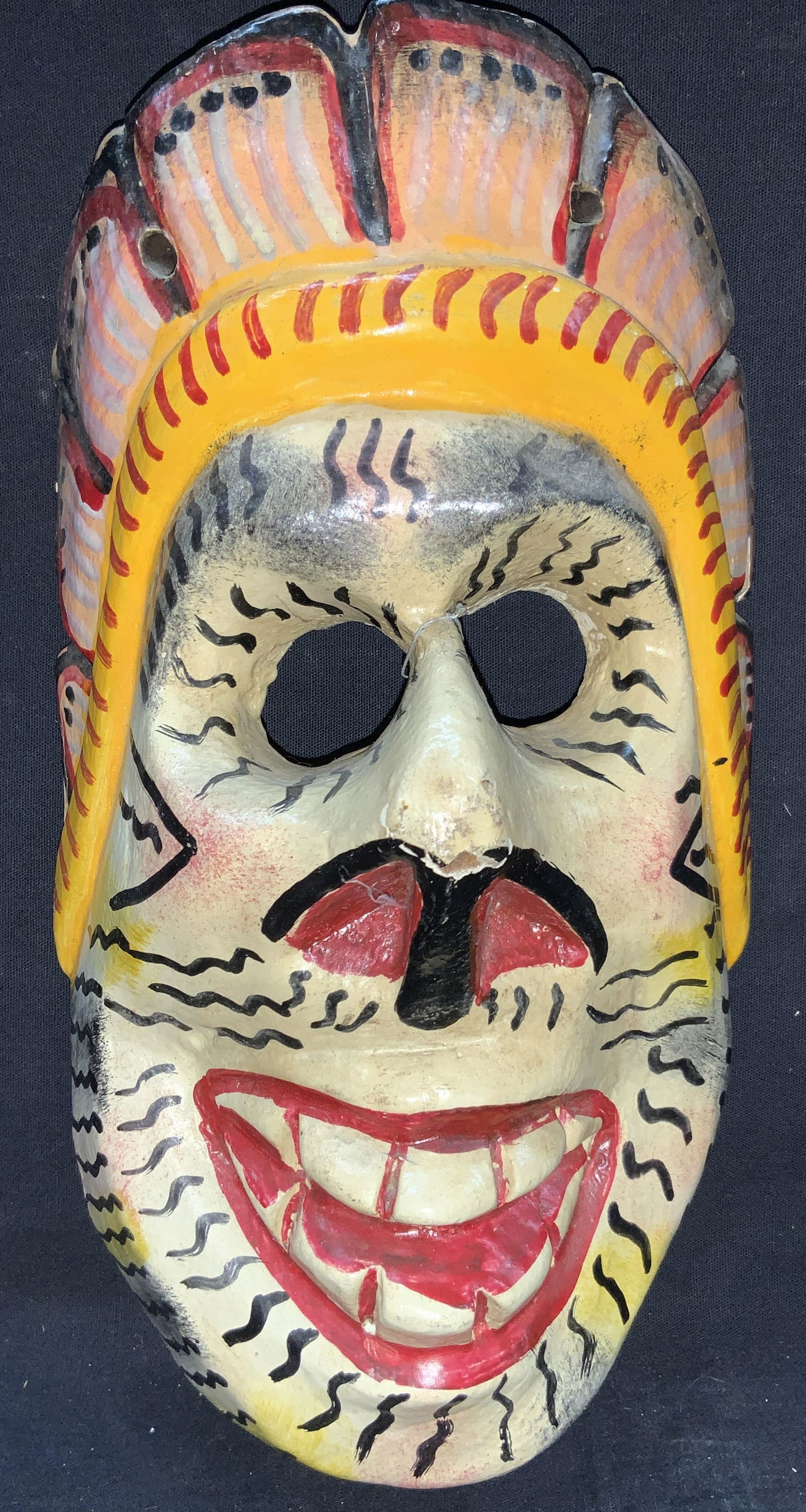 Carved Wooden Hand Painted Mexican Folk Art Mask: Carved wooden mask, hand painted with large nose and open mouth with large teeth and head piece and carved out eyes. Marked on backside sticker, made in Mexico. Approximately 11 inches long. Moderate
