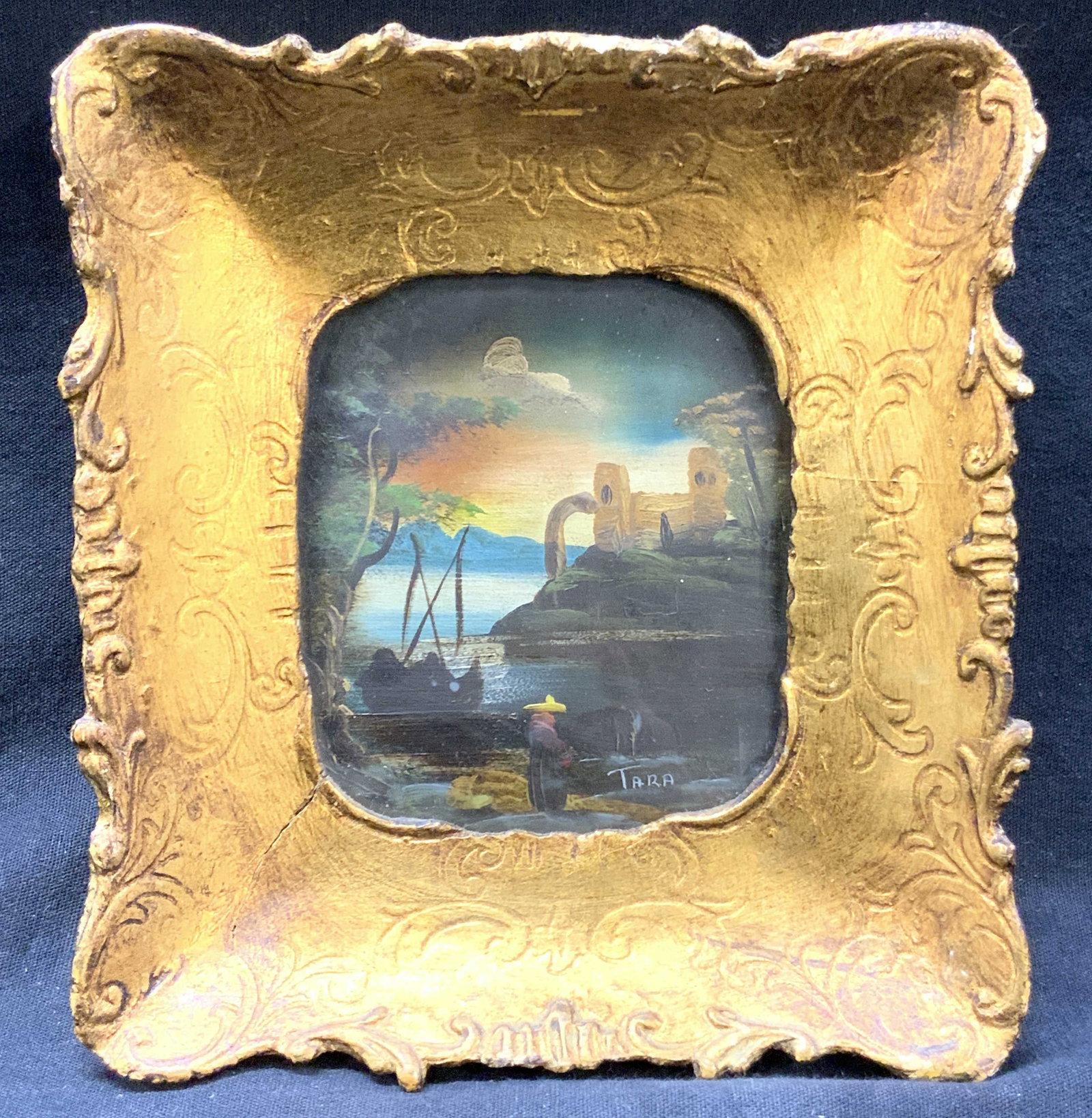 Tara Signed Landscape Oil Painting: Signed on lower right corner Tara, marked on backside, an original painting from Tara Productions. Depicts a person in the foreground of a landscape with a clay building in the background. Framed in g