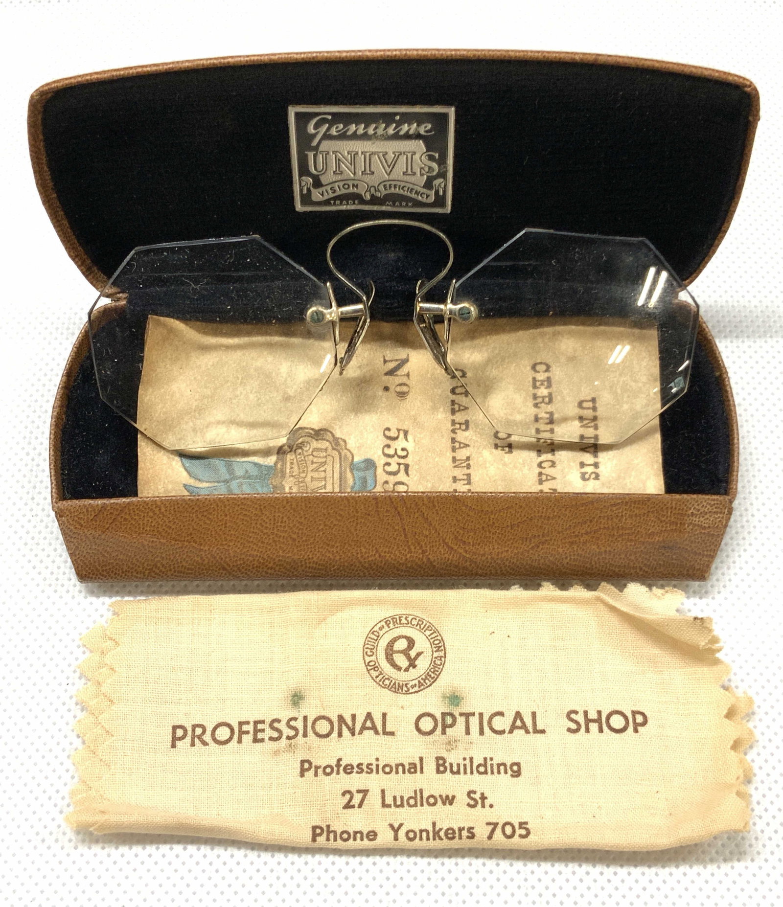Vintage Univis Bifocal Spectacles W Case: Pair of vintage bifocal spectacles with no frames. Marked on interior on brown case . Interior is lined with cobalt black toned felt. Nose piece to glasses are marked E.B.M. Inter of lid reads Genuine