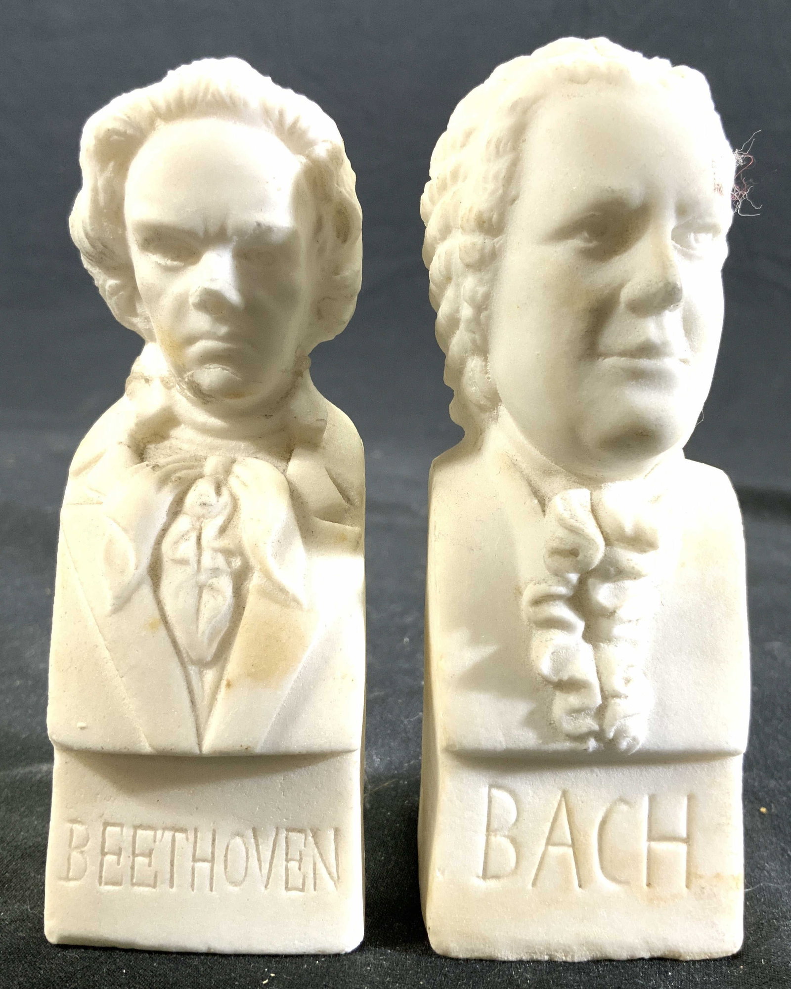 THE IMMORTALS Lot 2 Plaster Composer Figures: Sides of each are inscribed The immortals. Bases are inscribed BACH the other BEETHOVEN. Each are bust figures of named composer. Each piece,is cream toned appears to be plaster, possibly composite. E