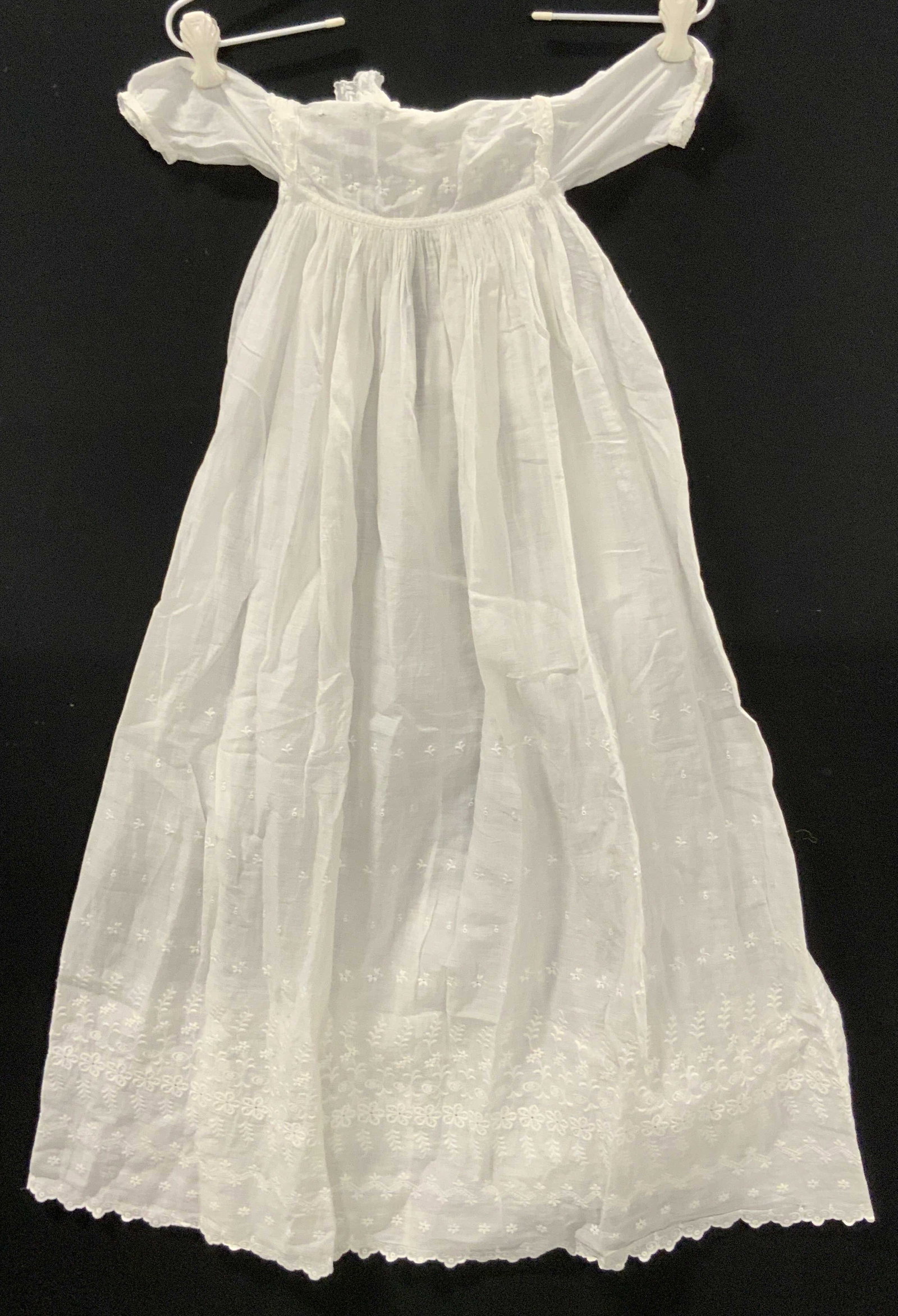 Vintage White Cotton Infant Dress: A vintage white cotton infant dress. Decorated with floral embroidery. Two button to reverse. Partially open to reverse. Dress measures approx. 38L x 16W in. Measured flat. Width measured arm to arm. 