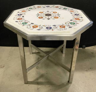 Octagonal Inlaid Stone Mosaic Top Metal Side Table: An octagonal side table comprised of an inlaid stone top and a silver tone metal base. White hued stone inlaid with blue, orange, and green stones. Floral and foliage designs. X shaped stretcher to th