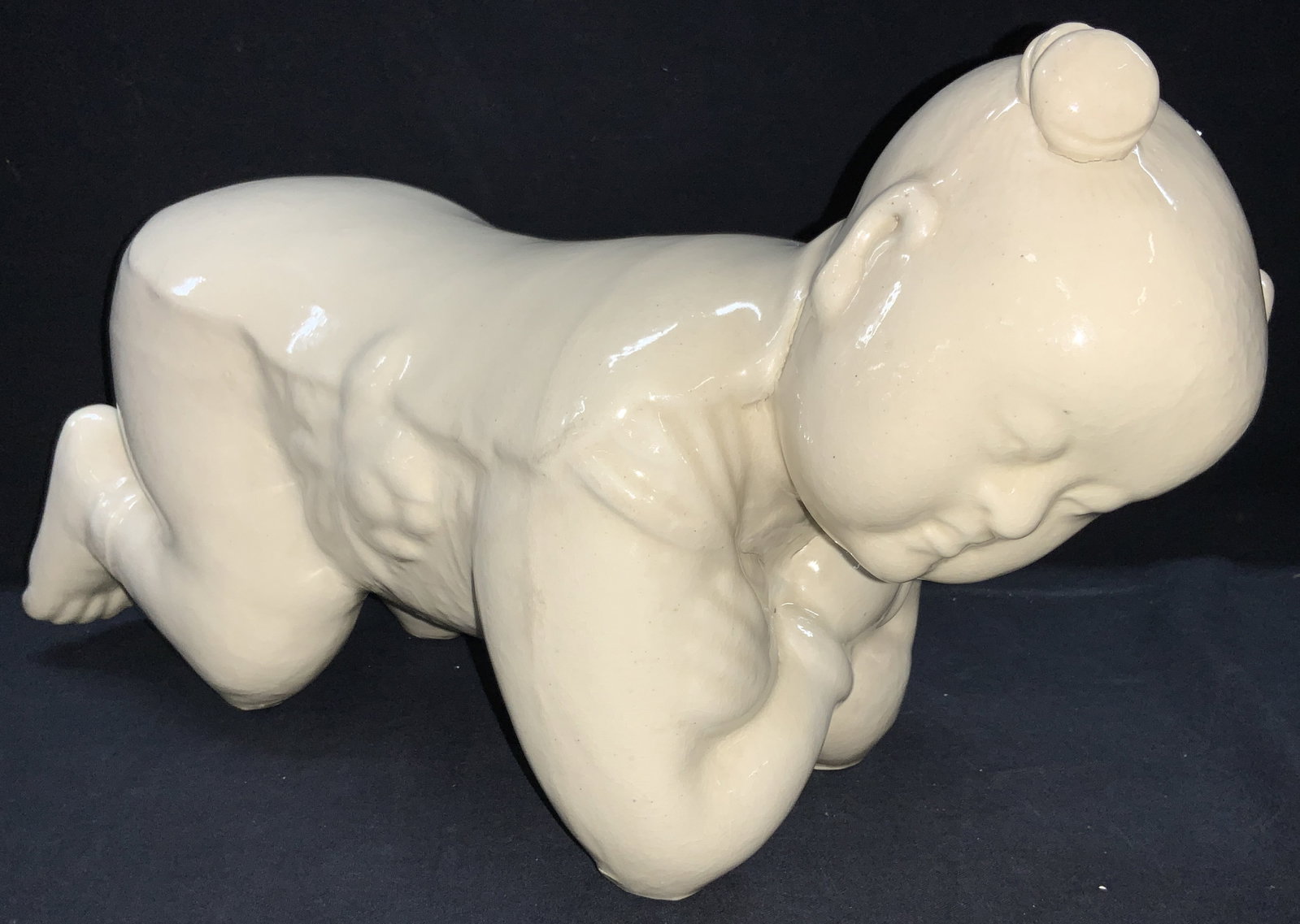 16 Inch Long Asian Child Pottery Pillow: An Asian pillow made of resemble a child kneeling and on their elbows. 16 in long by 8.5 in tall by 6 in long. Moderate wearing to underside. Crazing throughout piece, cracks, and losses to finish. As