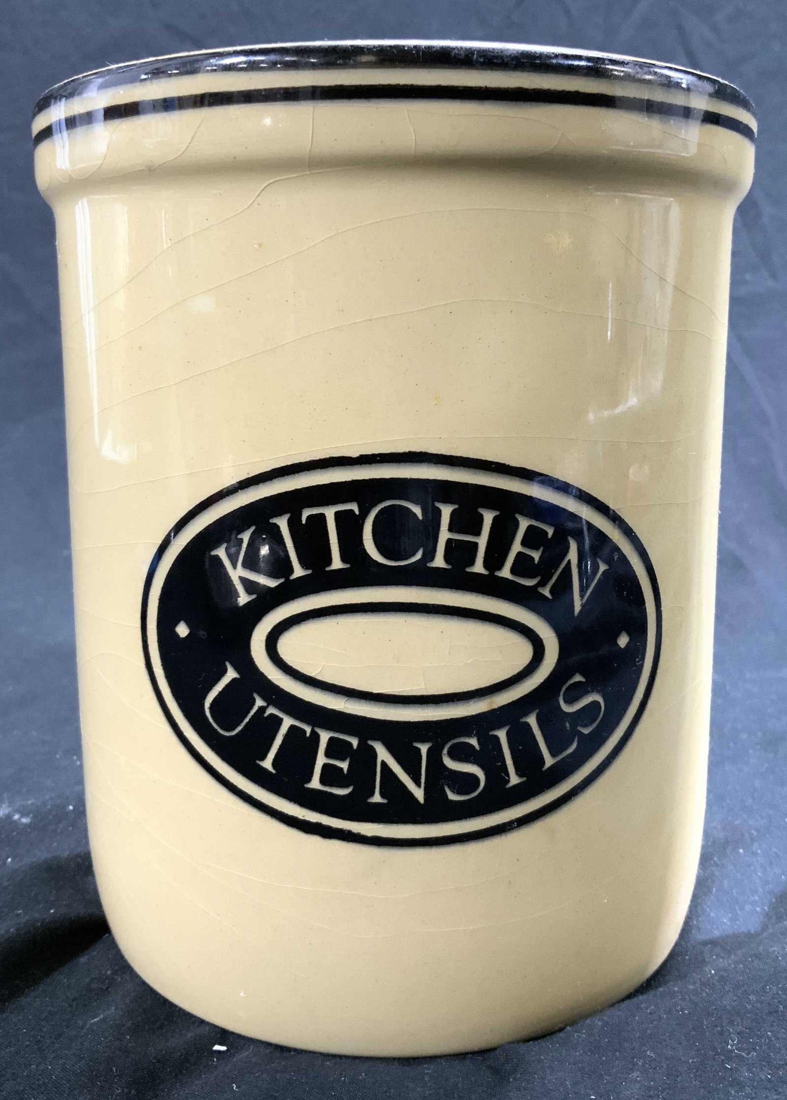 TGG GREEN LTD Porc Kitchen Utensil Holder: Underside is marked TGG GREEN LTD CHURCH GRESLEY MADE IN ENGLAND. Piece is yellow and black toned, reads KITCHEN UTENSILS on frontside. Vessel measures approx 5.75 inches tall 4.75 inches wide. Kitche