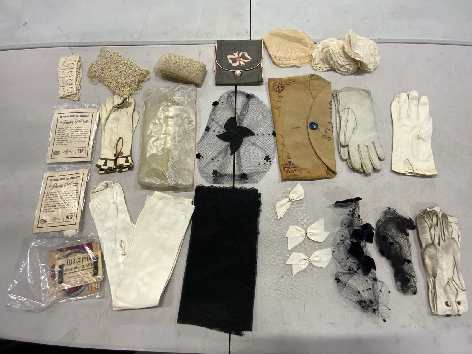 Group Lot Vintage Gloves, Hair Accessories & More: A group lot featuring vintage gloves, hair accessories, and lace accessories. Some pieces are attached to their original packaging. Largest gloves measures approx. 4.5W x 20L in. Some pieces have evid