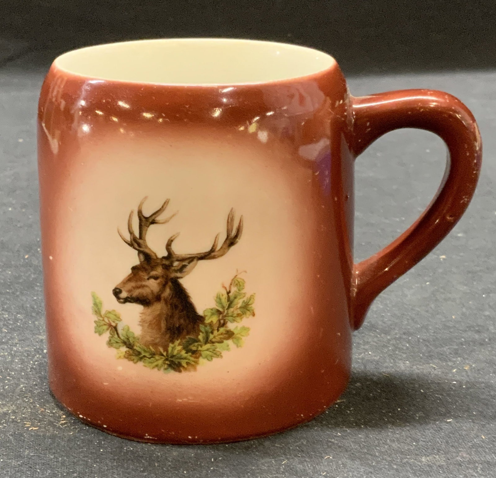 Vintage German Ceramic Deer Mug: Vintage German ceramic mug with deer motif. Measures approx. 3 3/8 x 3.5 inches. Some surface wear consistent with exposure. Marked Germany to underside. Mug, German mug, deer mug, tableware, table ac