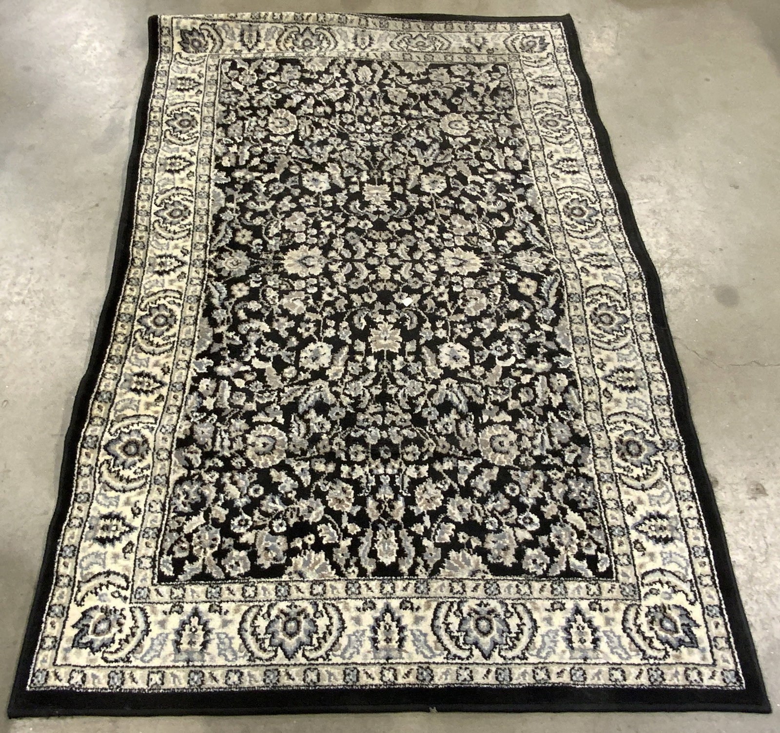 Vintage Floral Area Rug: A vintage floral area rug. Comprised primarily of gray, blue, cream, and black hues. Measures approx. 58L x 39.5W in. Appears to be crafted from wool. Some wear consistent with age and use. Area rug, 