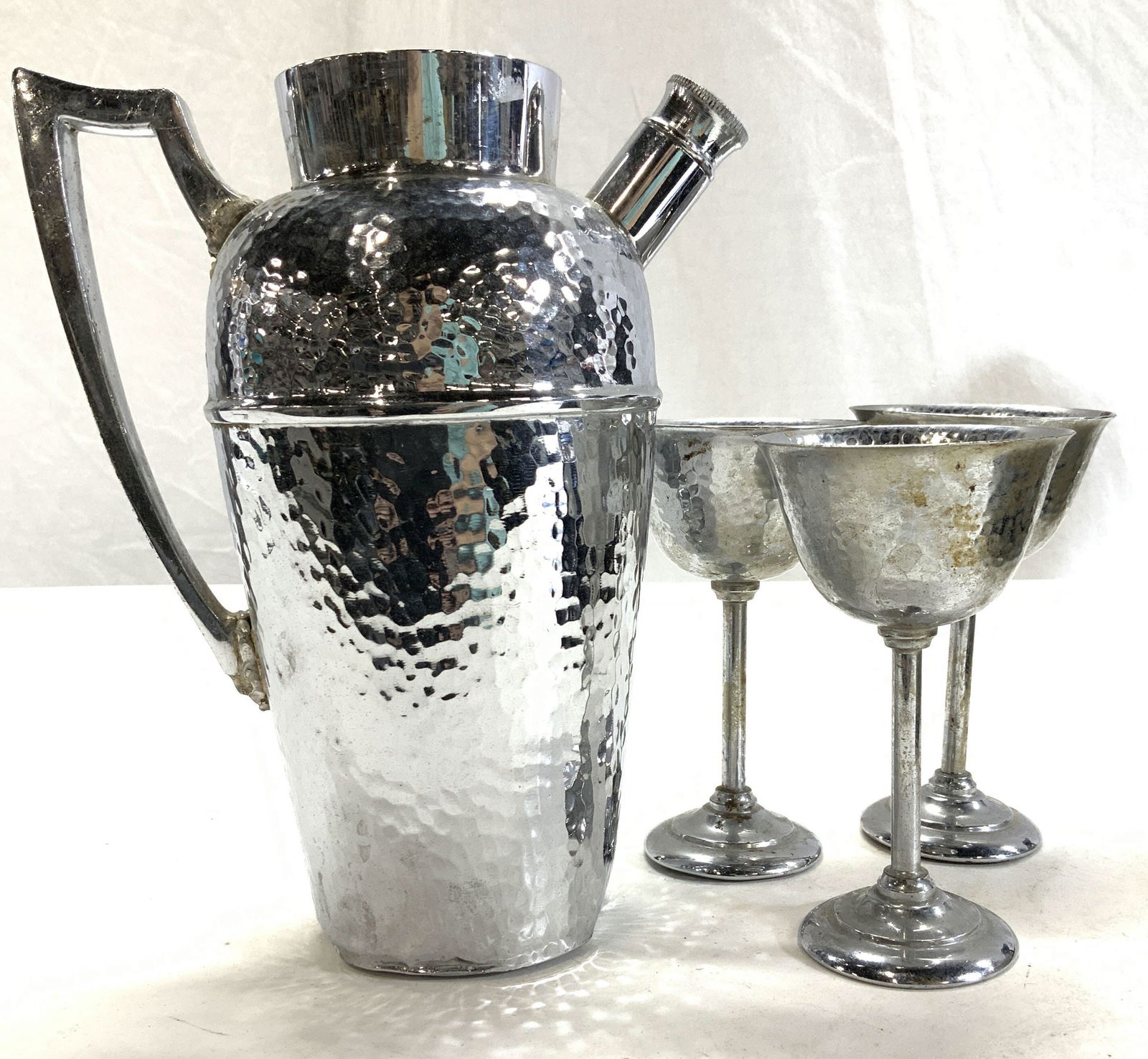 JF Hammered Silver Plate Goblet & Pitcher Set 4: Pitcher and 3 stem goblets, hammered silver plate , marked JF with trademark crown and E.P.N.S . Pitcher has dents on lower rim. No lid. Screw cap on spout. Goblets measure 5 x 3 in. Ht x diameter. Ba