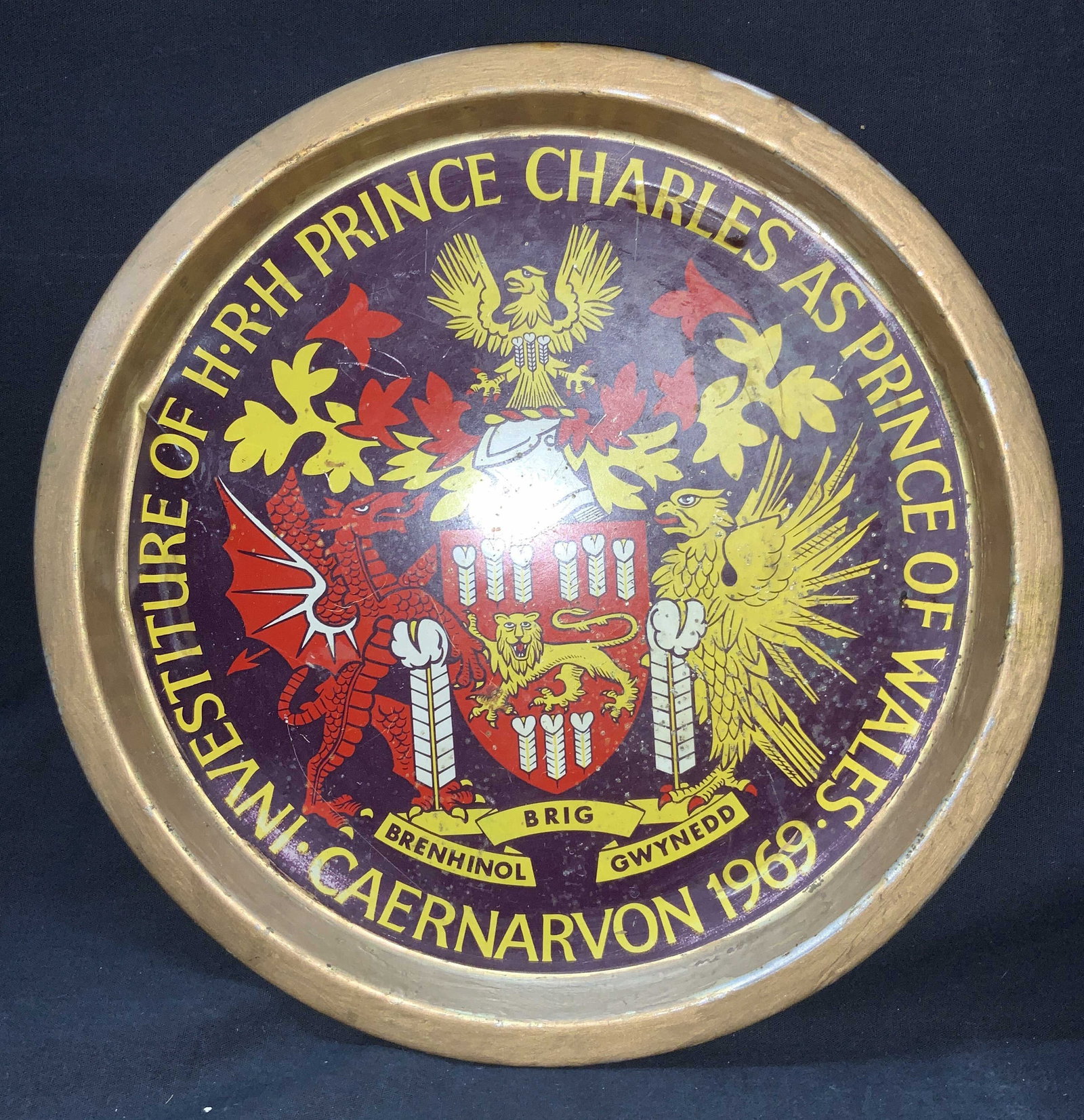 Vintage Prince Charles Of Wales 1969 Pewter Plate: Copper and brass toned pewter plate with center design of a dragon and a lion against a shield with test around the center reading Investiture of H.R.H Prince Charles As Prince Of Wales, Caermarvon 19