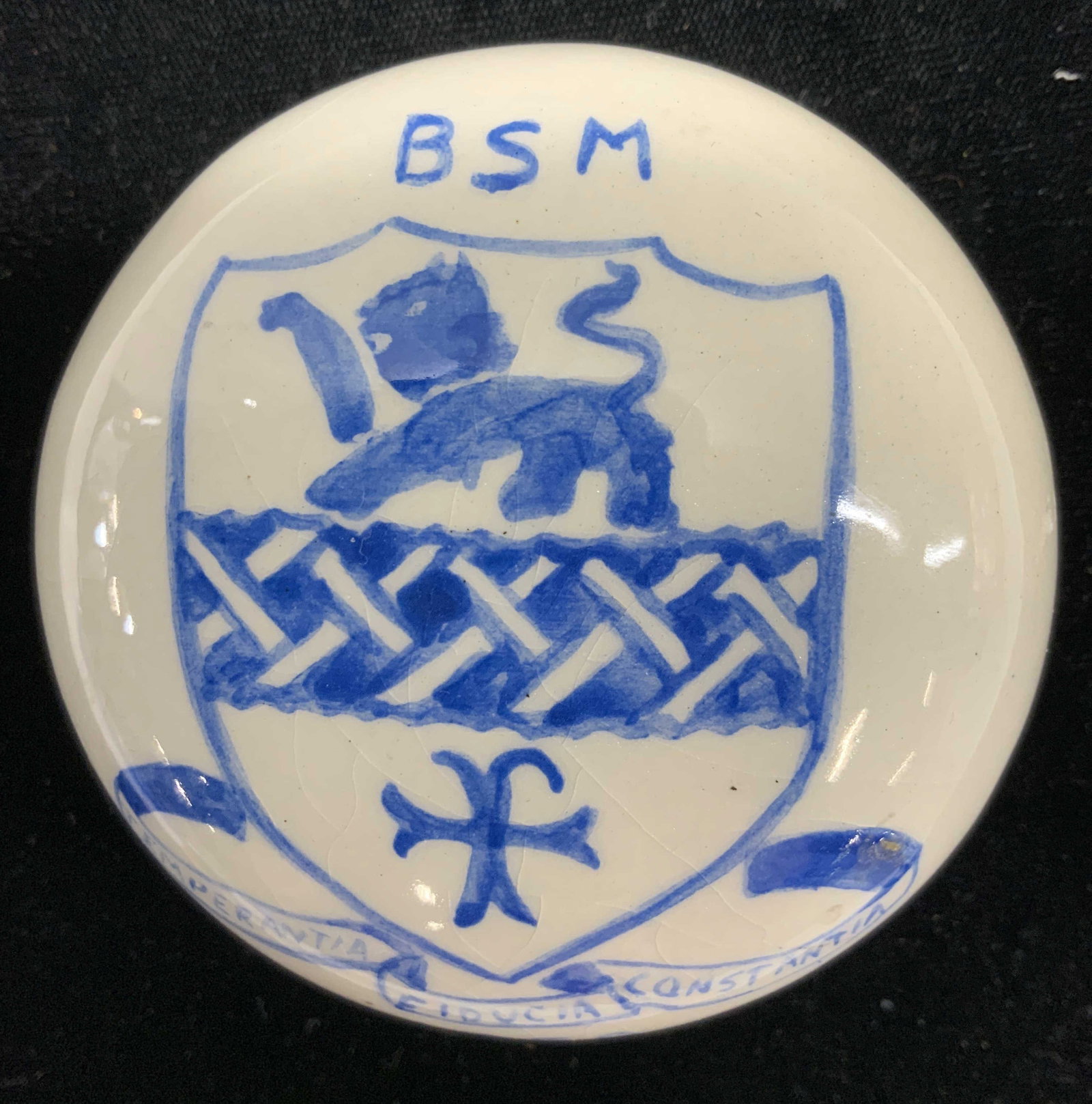 Porcelain Handmade Paperweight, 1959: Hand painted paperweight, made of white porcelain with lion and cross within shield Reads BSM—-Temperantia Fiducia Constantia- 1959 3.25 in. Diameter. Glaze crazing. Paperweight , hand made porcelai