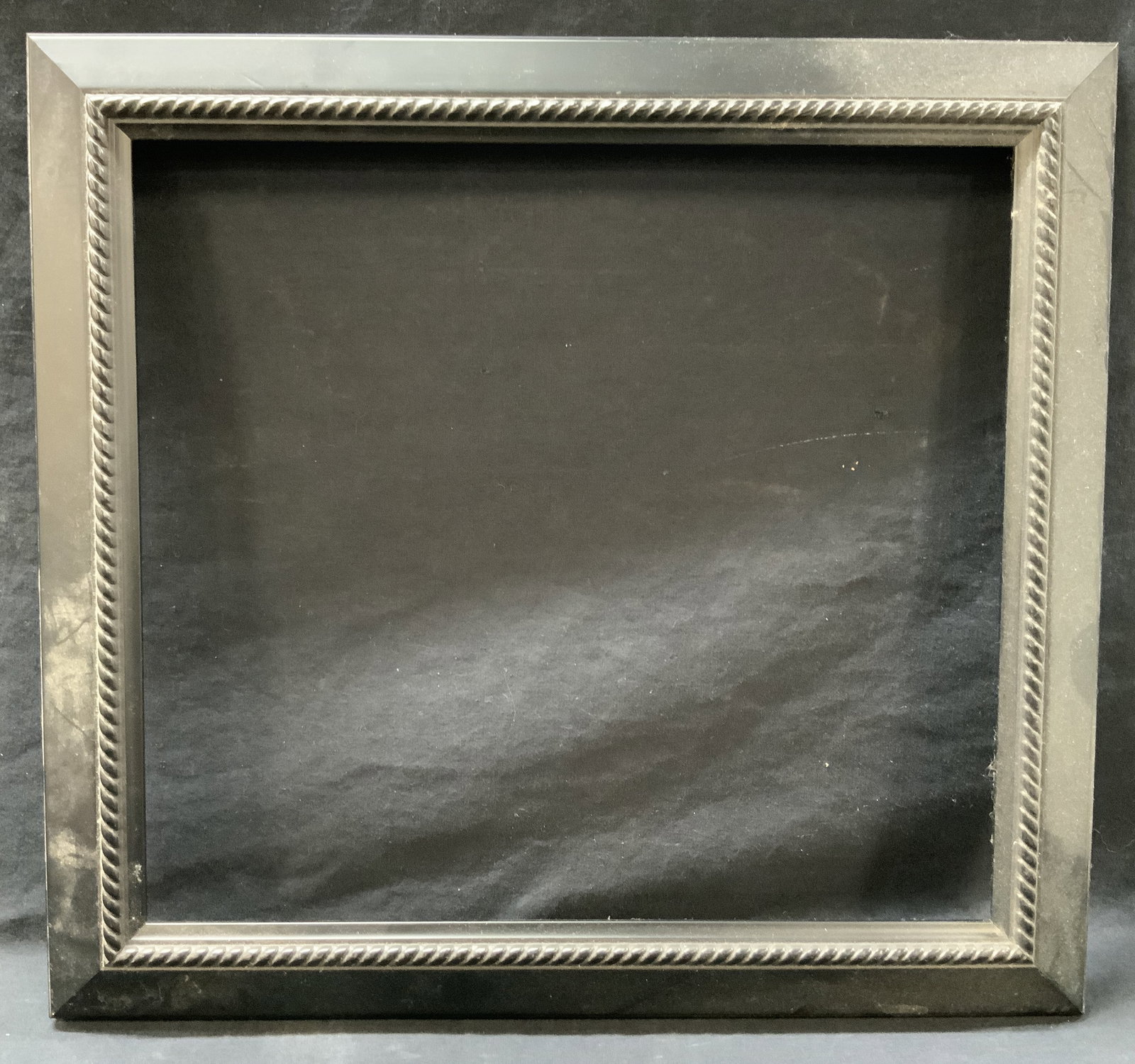 17.5 x 19 Black Wooden Wall Frame: Black wooden wall frame with braid pattern on inner edge, approximately 17.5 x 19 inches window measures 13.75 x 15 inches. Moderate wearing to frame and to backside. Black wooden framed wooden frame,