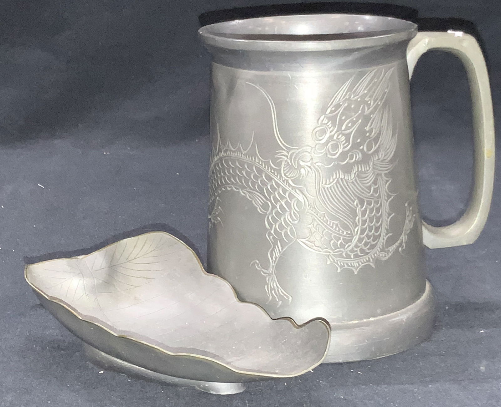 2 Etched Pewter Tabletop Accessories: Lot of 2 ether pewterware, pewter trinket dish made to resemble a leaf with etched veins in the center, and a pewter tankard, with etched motif of a Chinese dragon on the side, approximately 4.75 inch